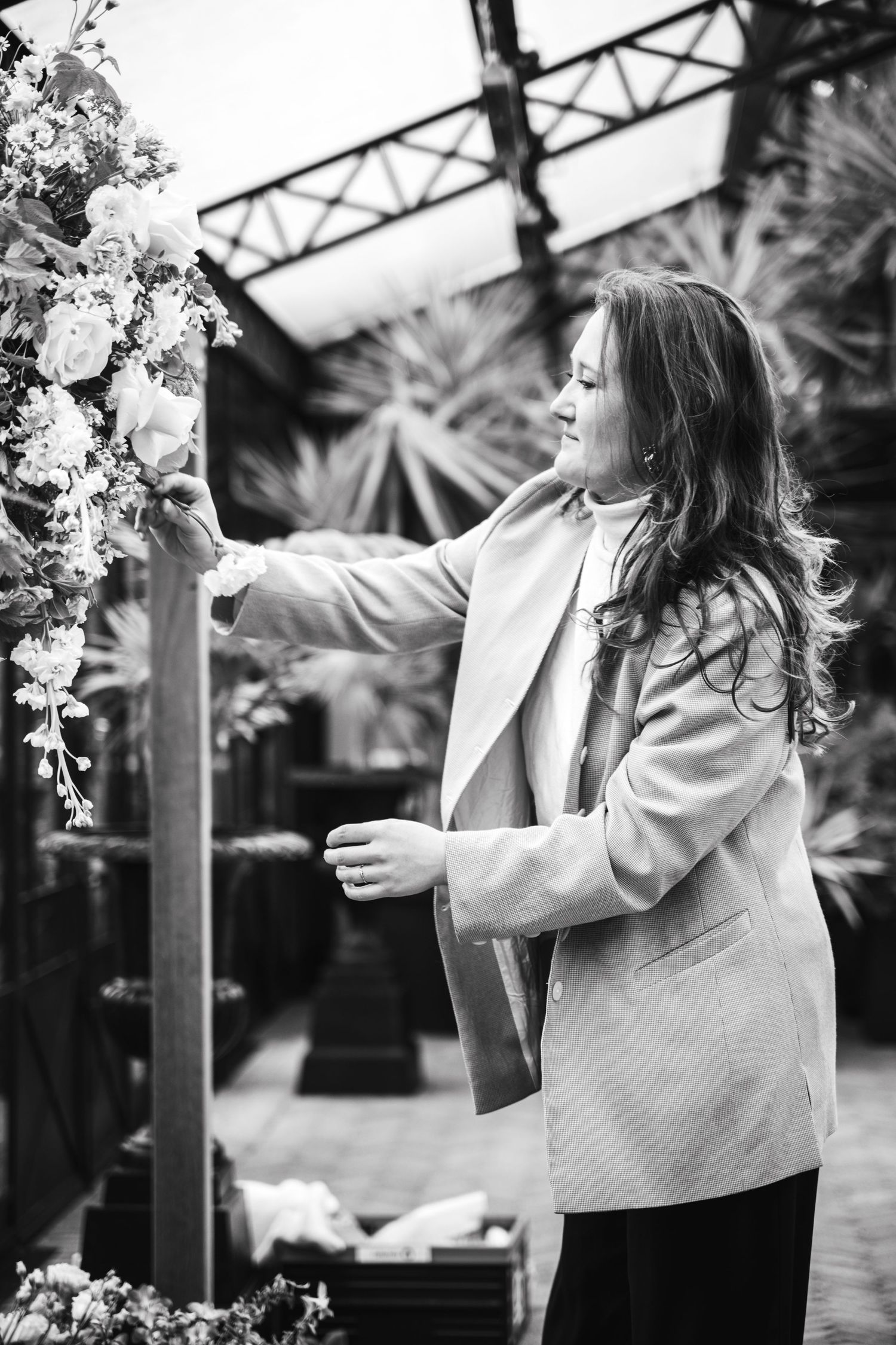 Een zwart wit foto van een vrouw die een bloemenstuk aan het maken is voor een huwelijk