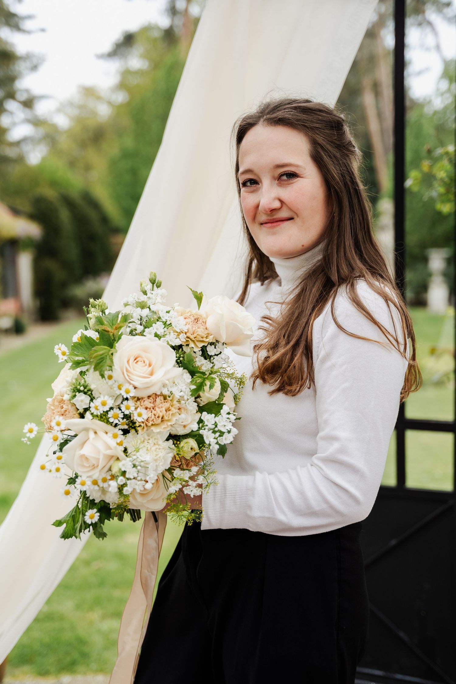 Een kleurenfoto van een bloemiste die haar bruidsboeket toont