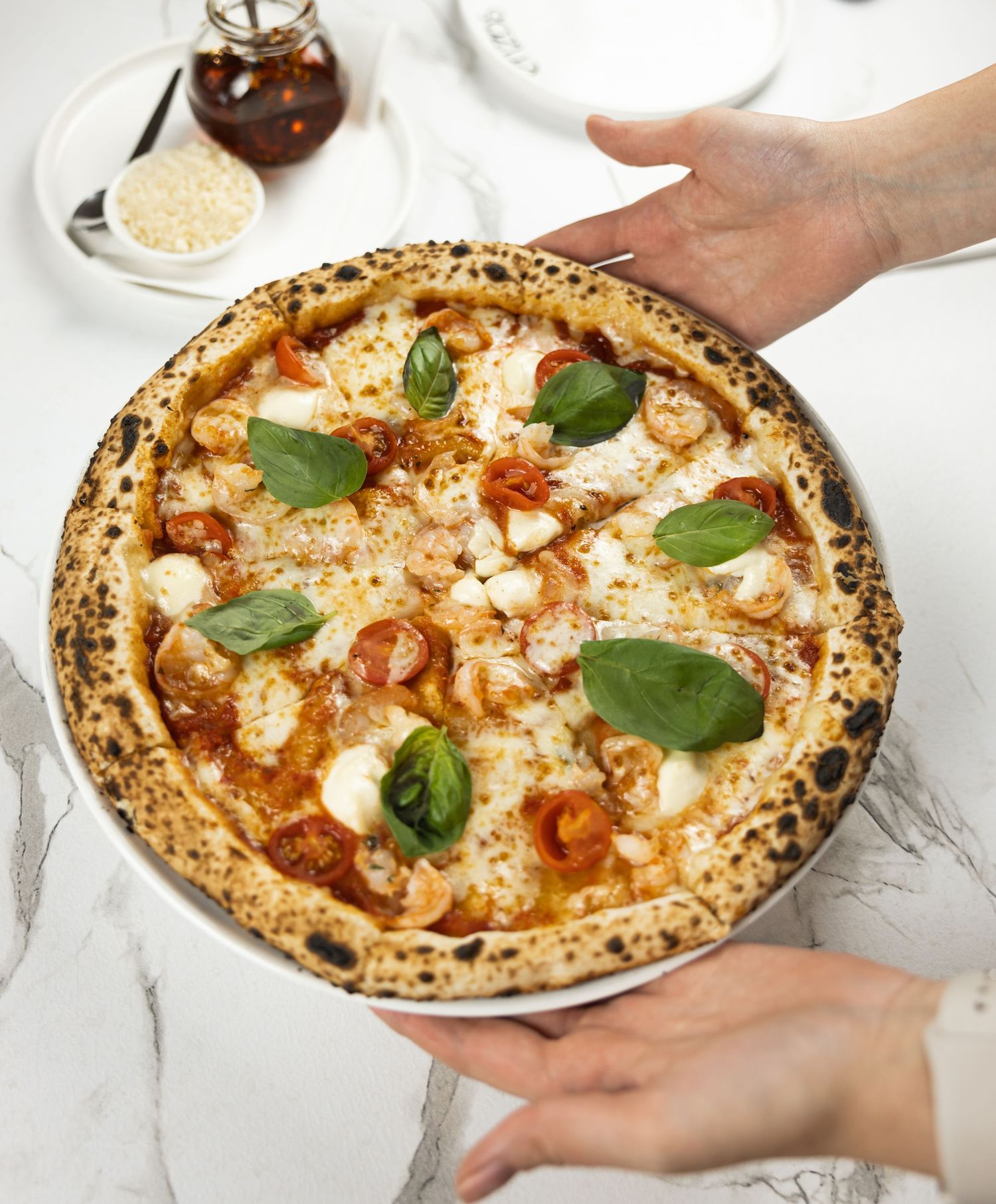 Top view of pizza with tomato, basil, and melted cheese.