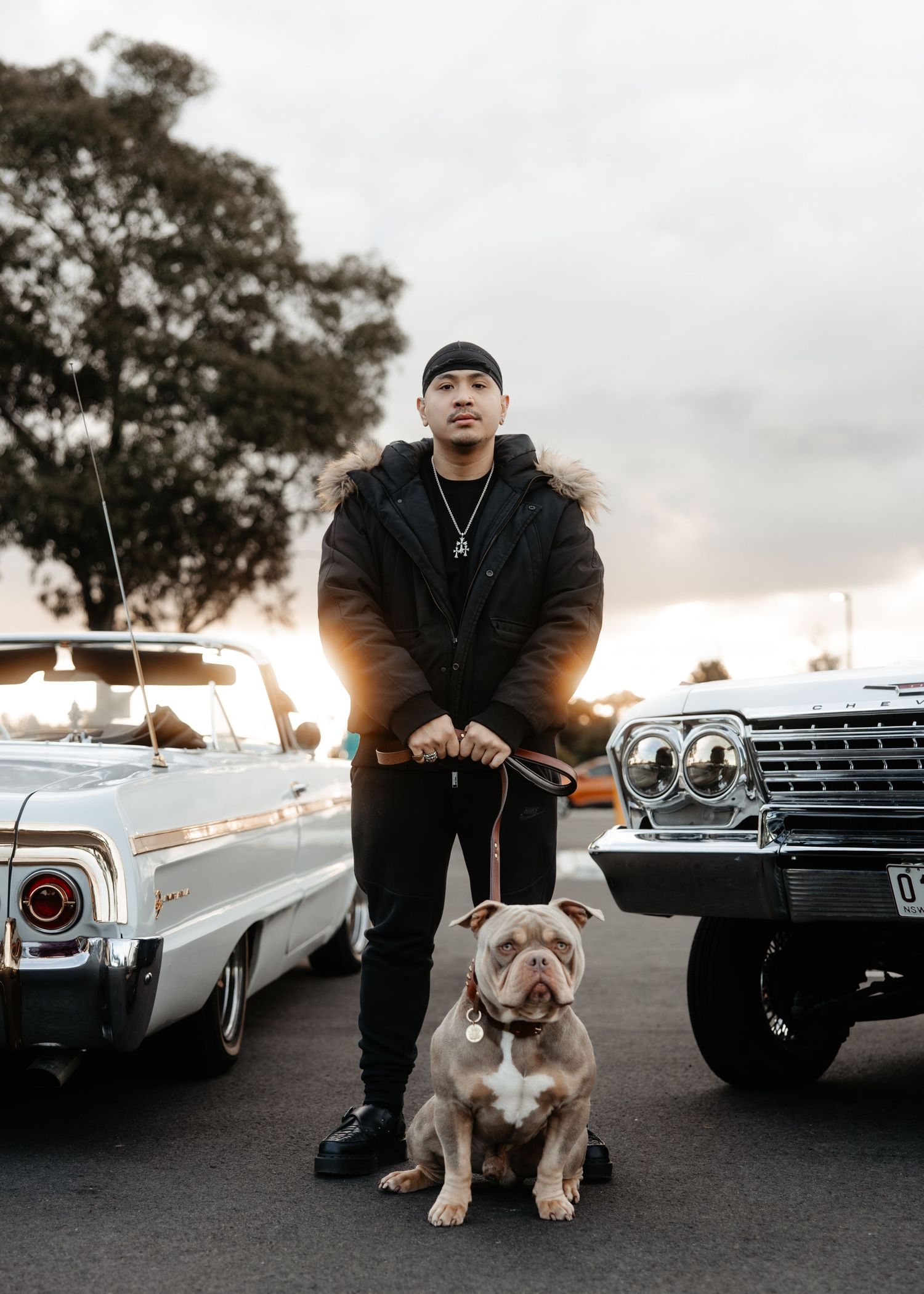 Man with dog and classic car at sunset, outdoor lifestyle moment.