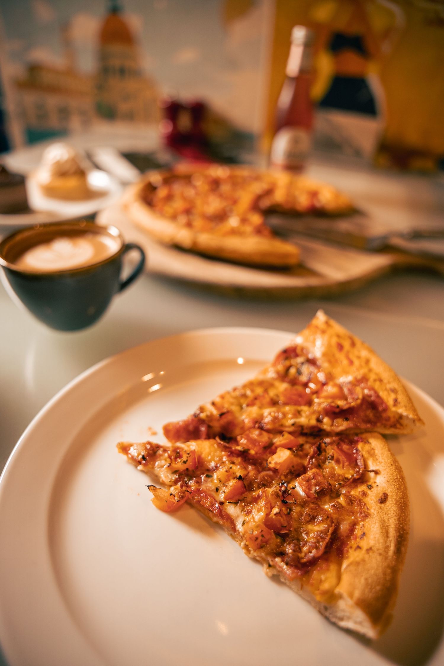 Slice of pizza served on plate with coffee, food photography detail.