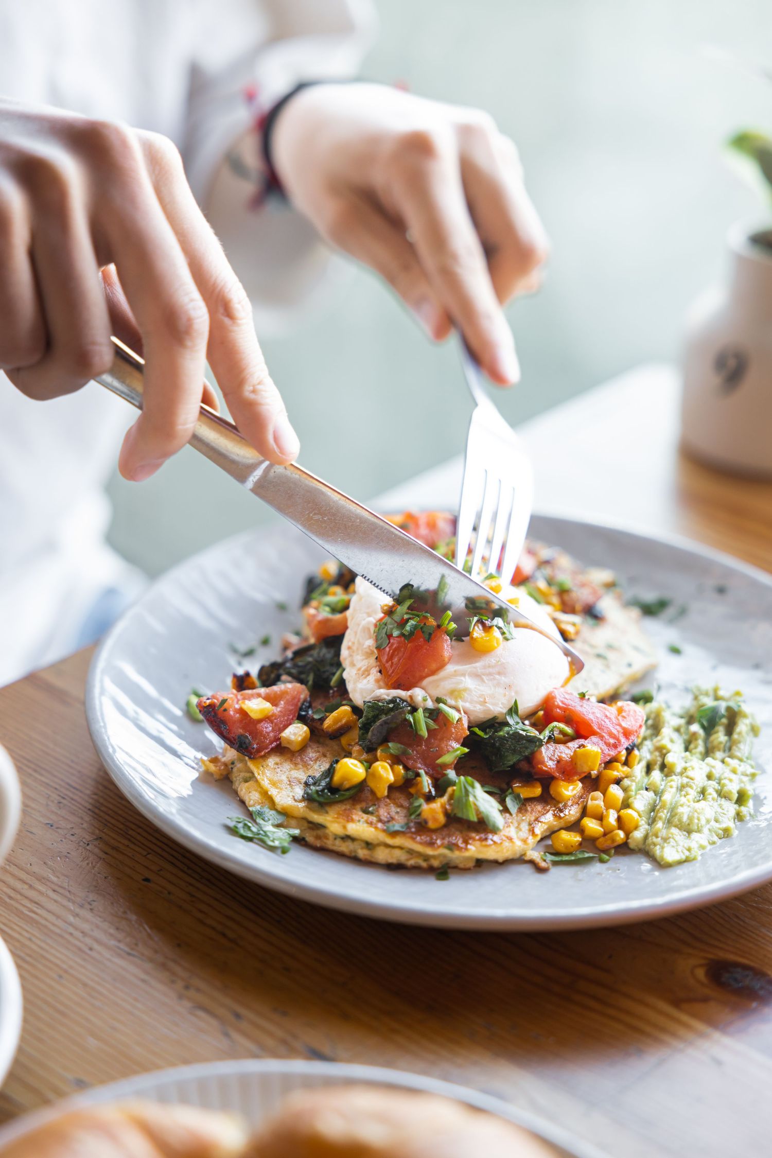 Hands serving a fresh salad bowl with greens and cheese.