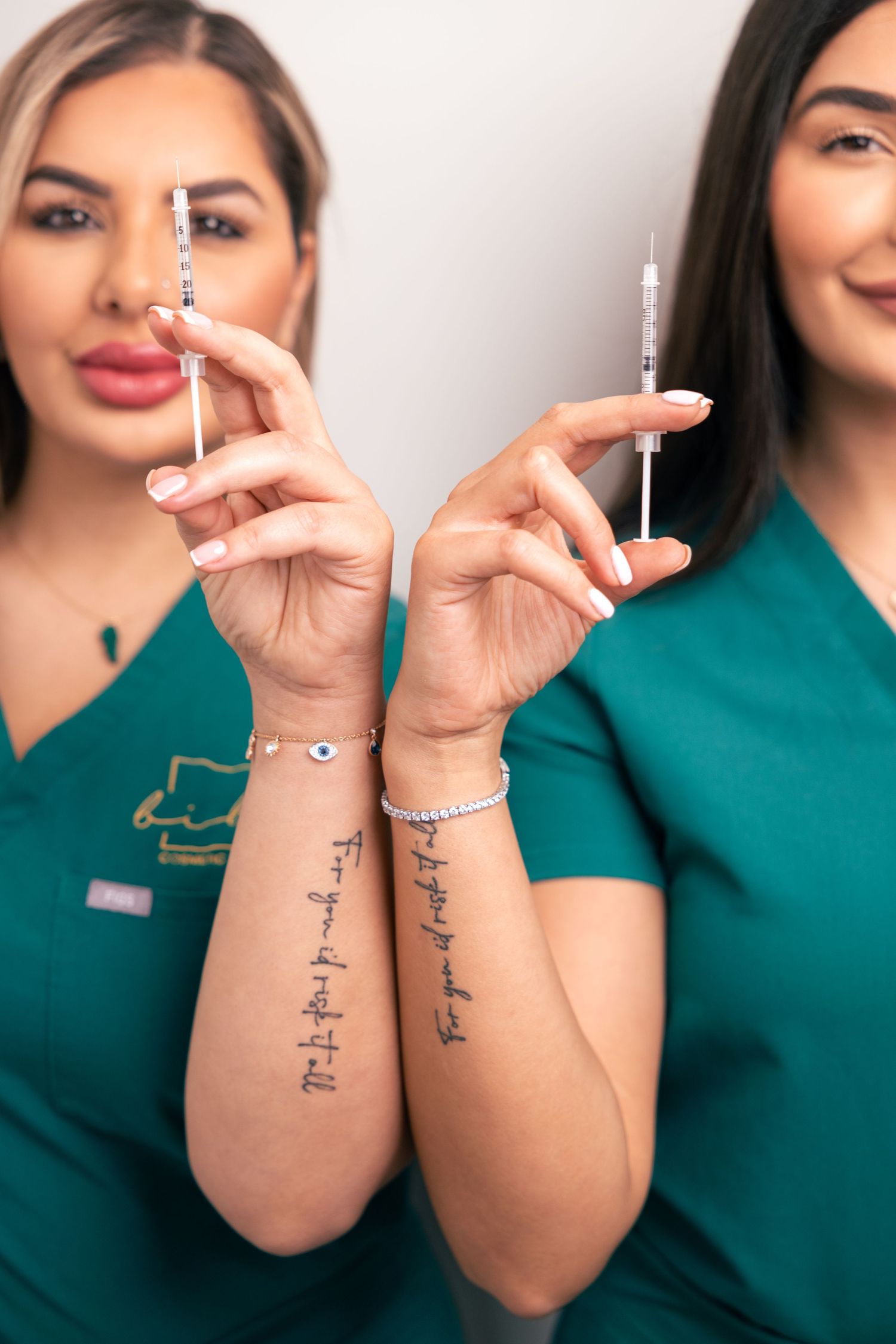 Two women in teal uniforms smiling, fun team portrait.