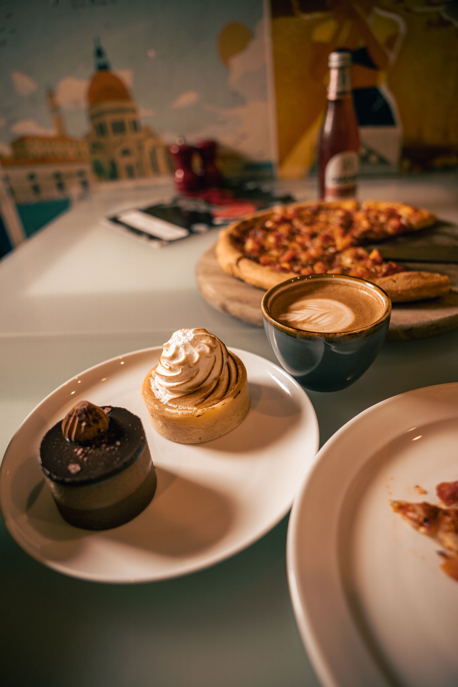 Pizza and desserts on café table, styled food photography scene.