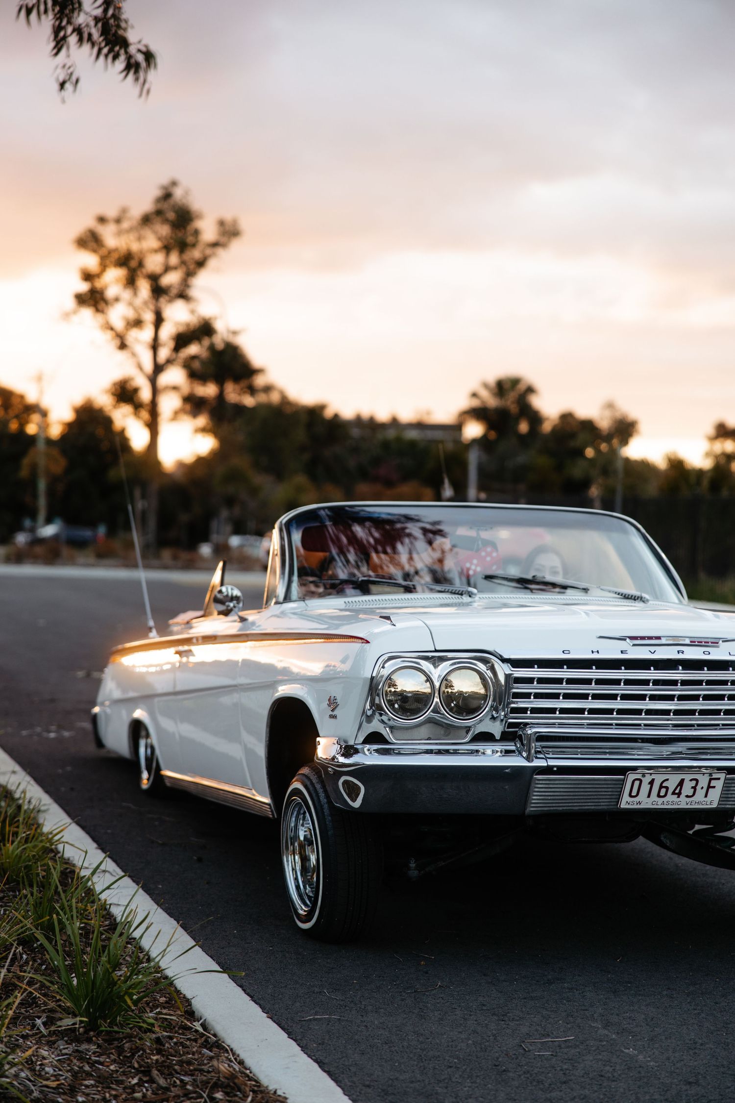 White classic car driving at sunset, cinematic road scene.