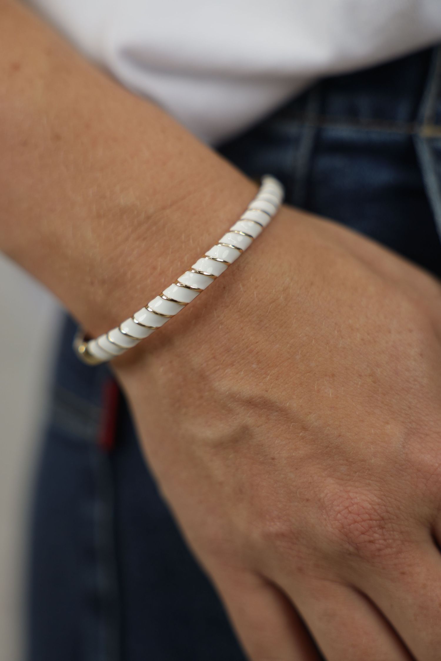 A close-up fashion detail photograph capturing a female model’s hand resting in the pocket of black pants, accentuated by a stylish bracelet