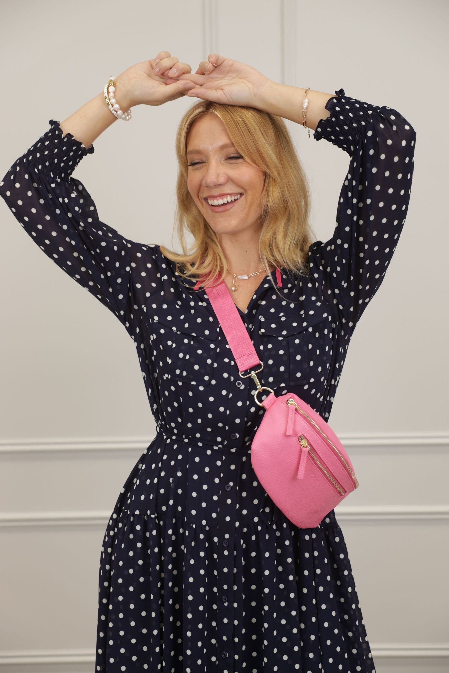 Woman in polka-dot dress with pink crossbody bag
