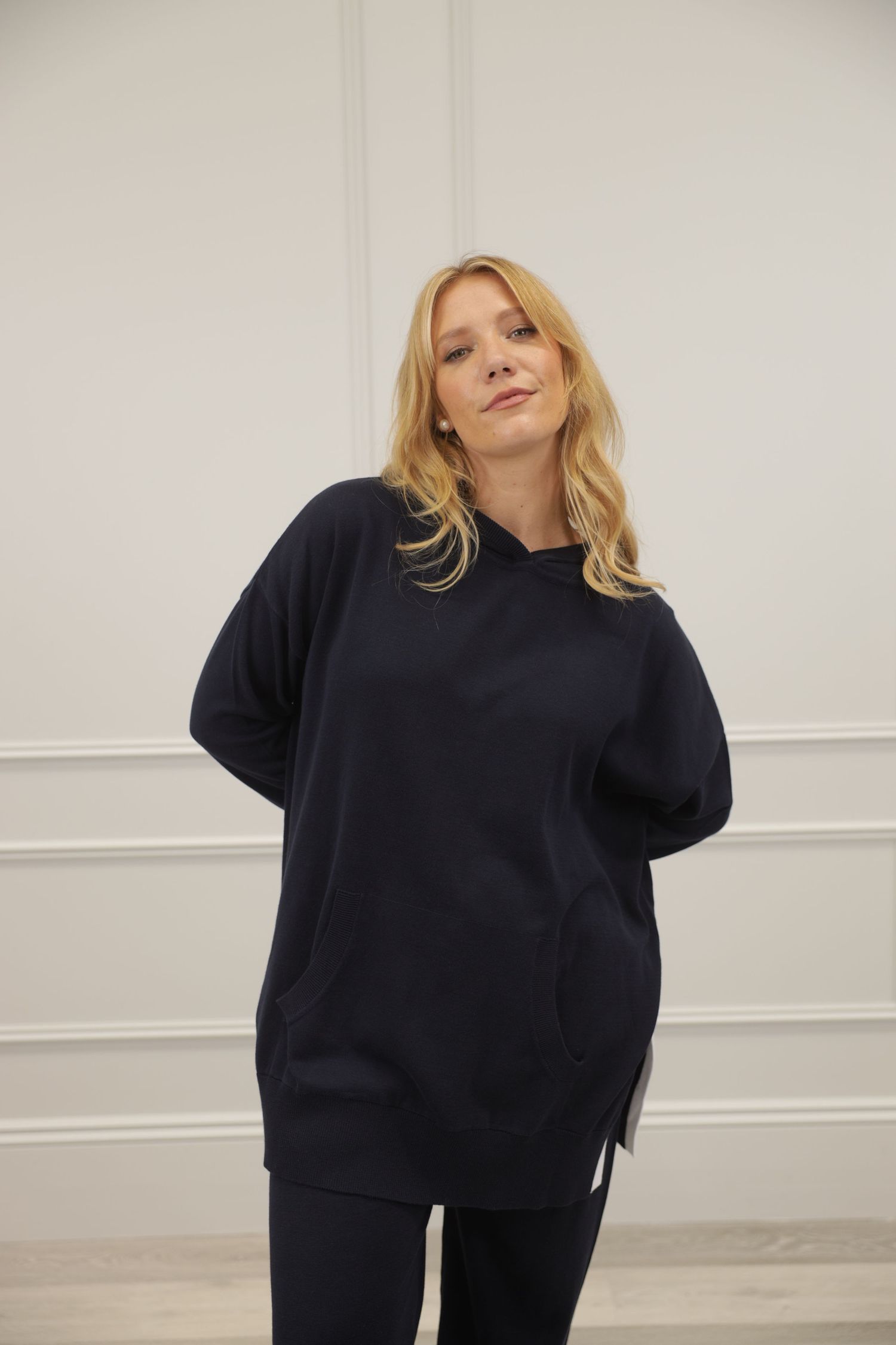 Blonde woman in loose dark sweater, cowboy shot portrait