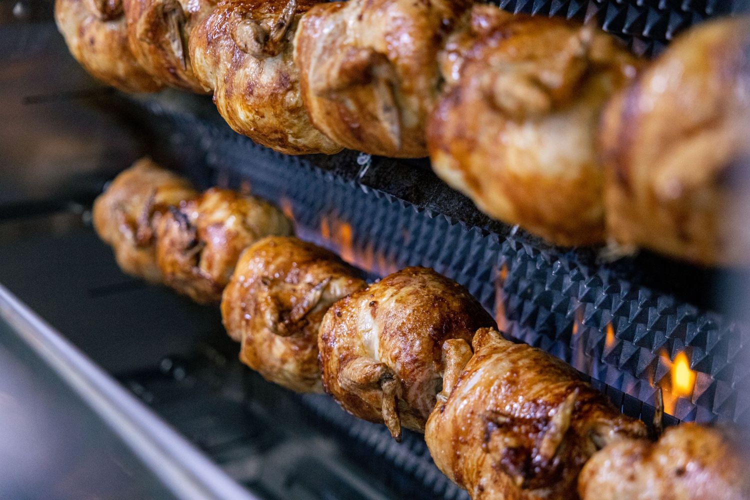 Golden rotisserie chickens roasting, close-up food photography.