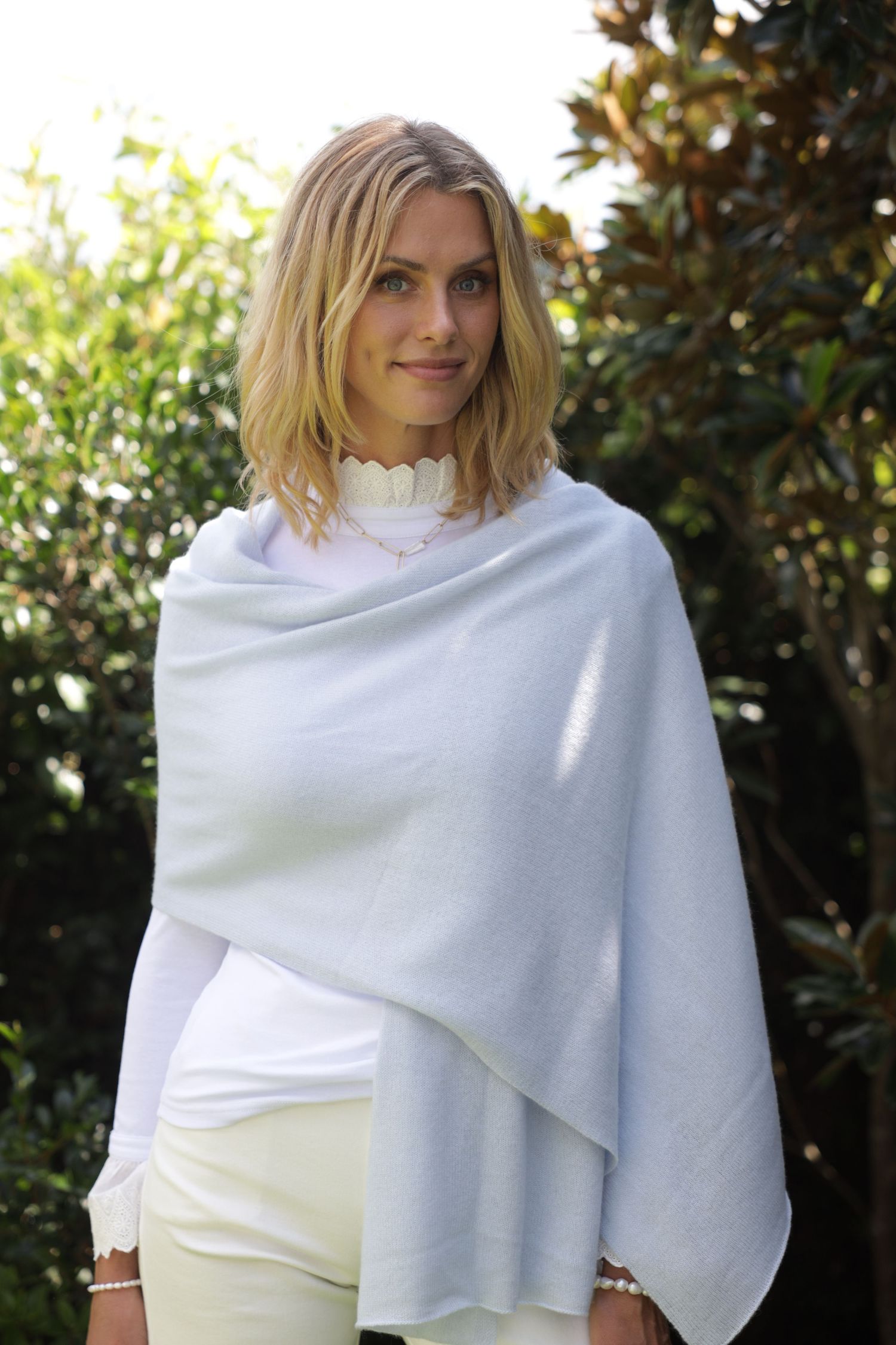Blonde woman outdoors in white top, casual lifestyle portrait in natural light.