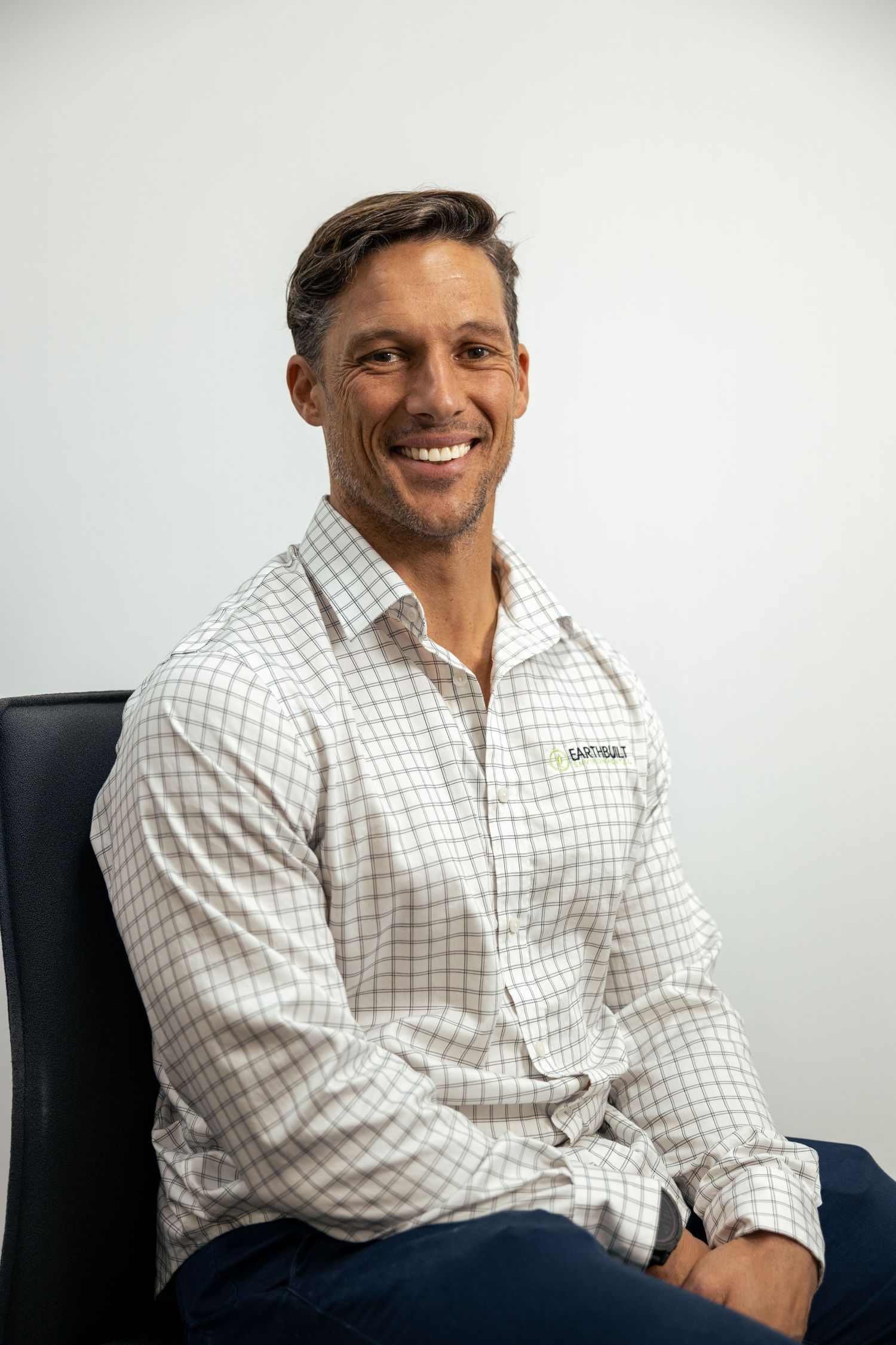 Professional portrait of smiling man in white patterned shirt, studio style.