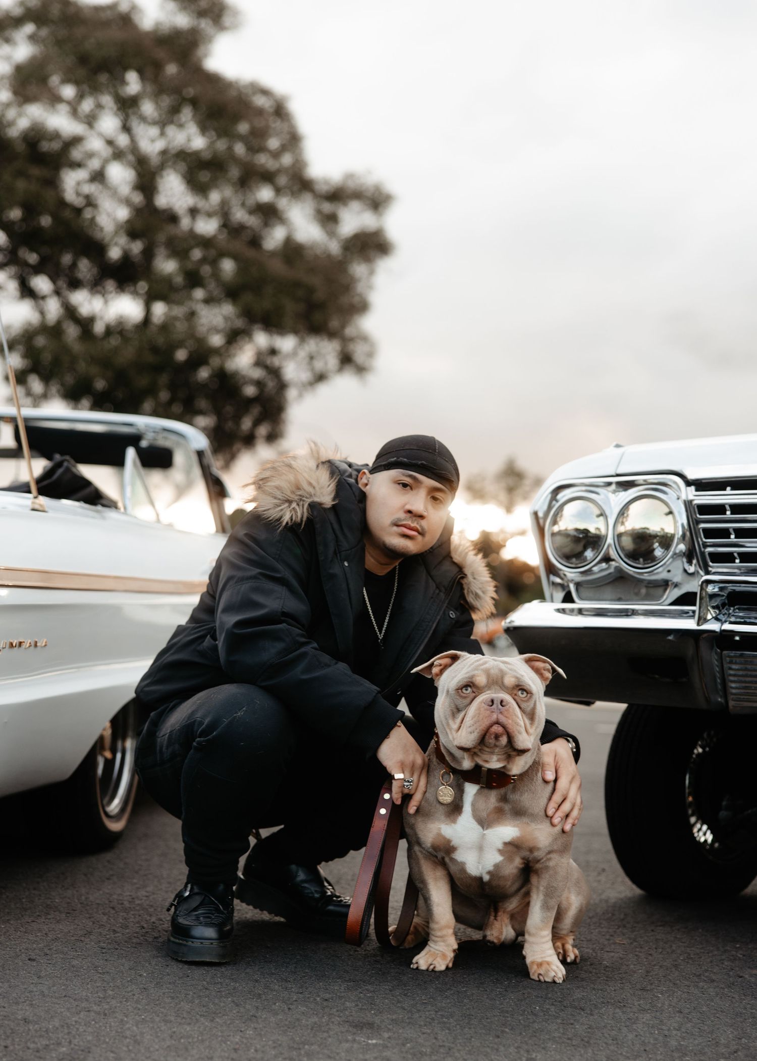 Lifestyle photo of man sitting on truck with dog, relaxed outdoor scene.