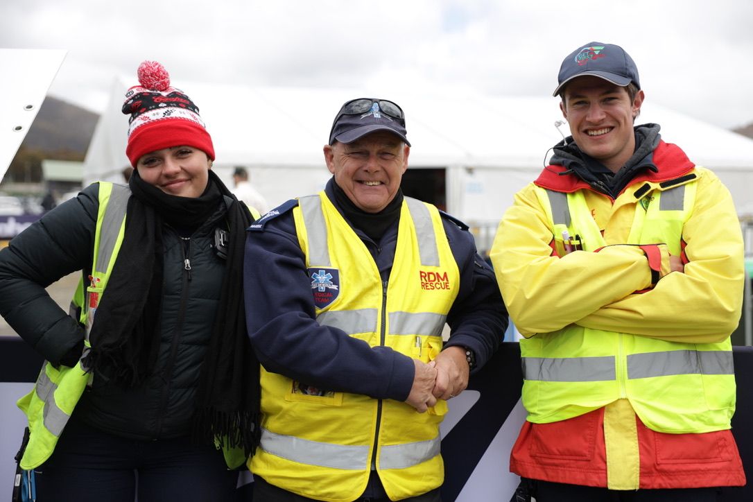 Event volunteers in bright jackets posing together, group shot.