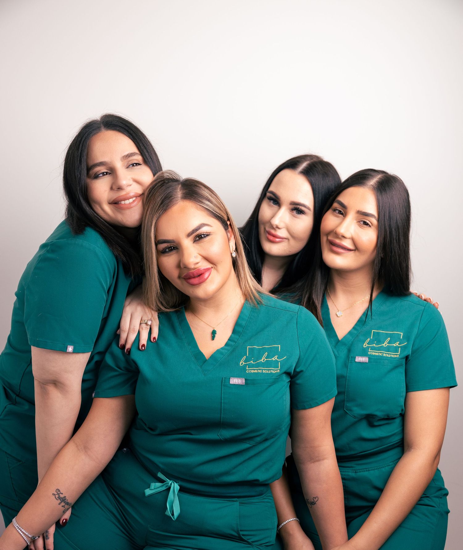 Group portrait of four women in teal uniforms, team photography.