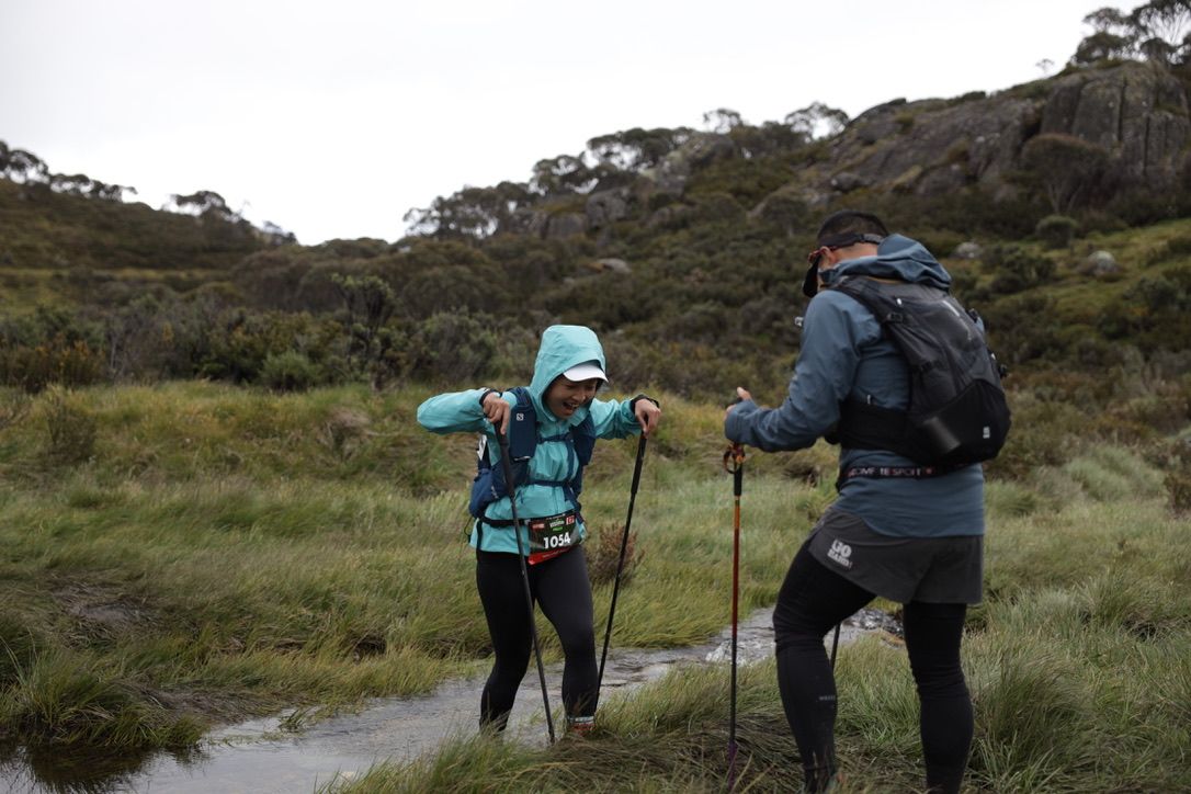 Two trail runners hiking rugged mountain path during race.