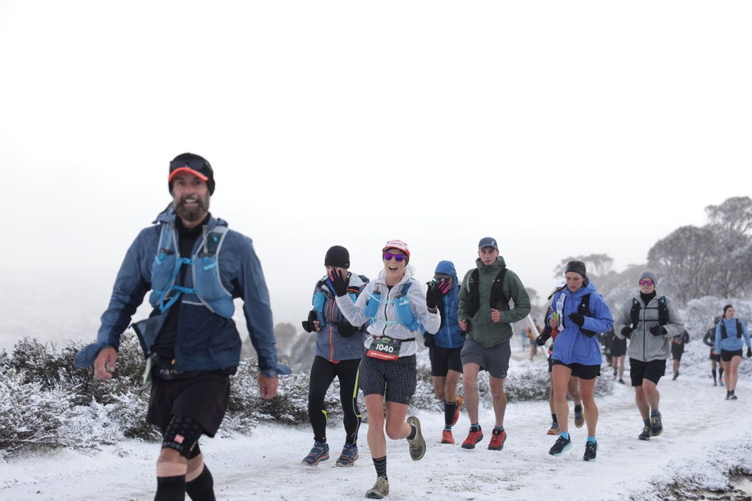 Pack of athletes running in mountain race, endurance event photo.