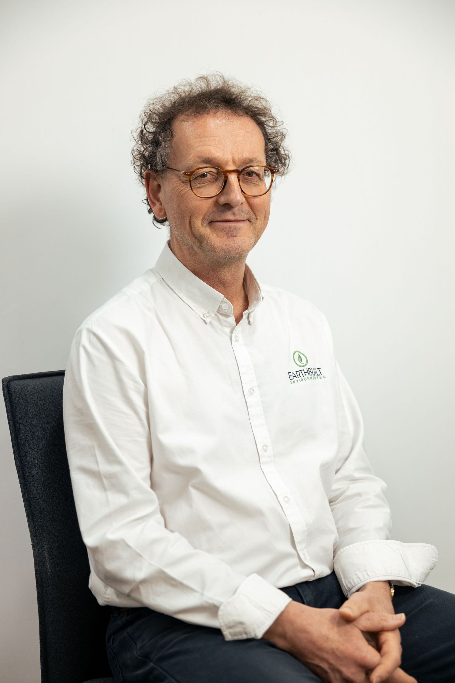 Professional headshot of man in glasses and white shirt, studio.