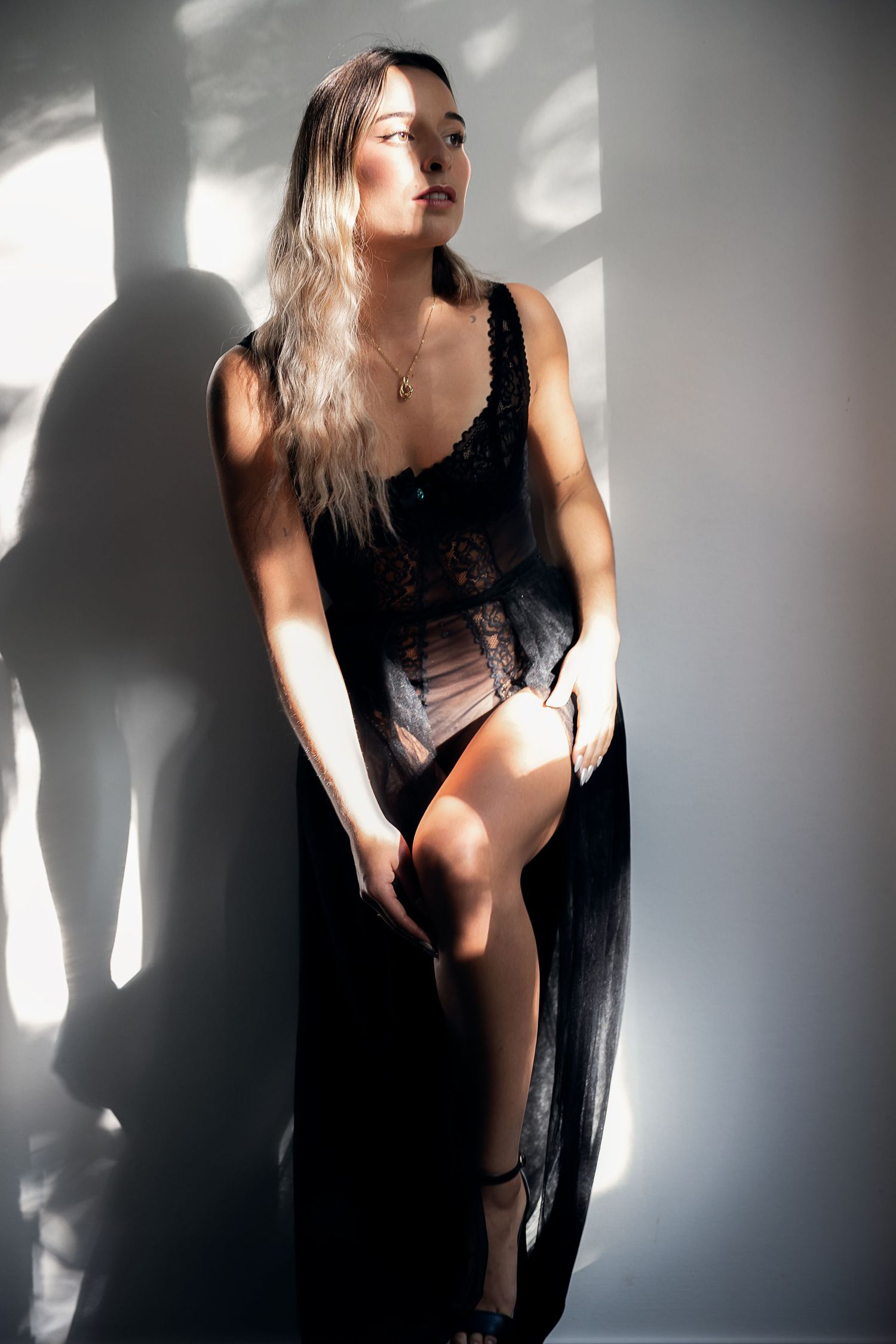 A dramatic artistic series of black and white photos showing a woman in a black dress with contrasting light and shadows.