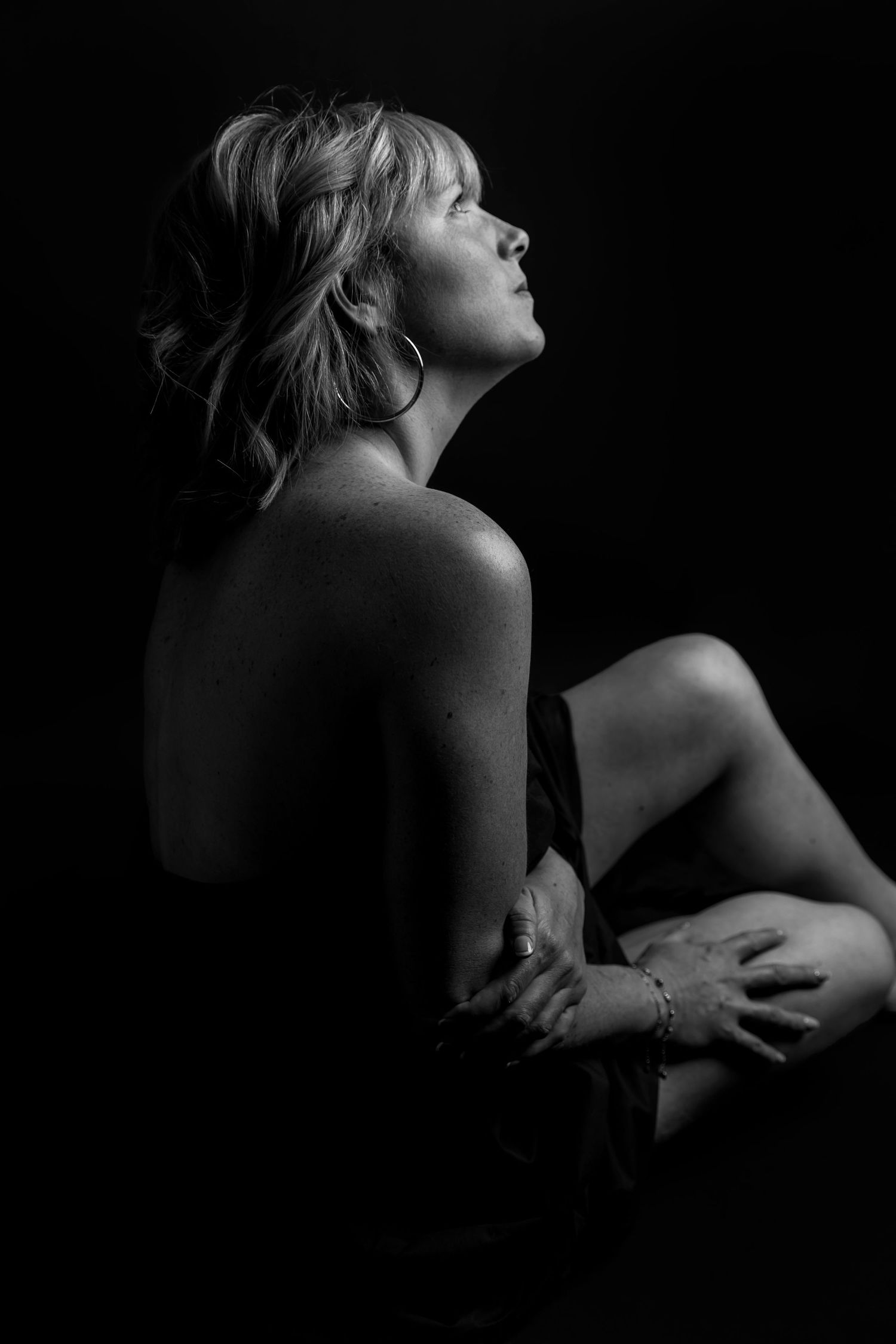Dramatic black and white artistic portrait showing silhouette of figure in profile against dark background.