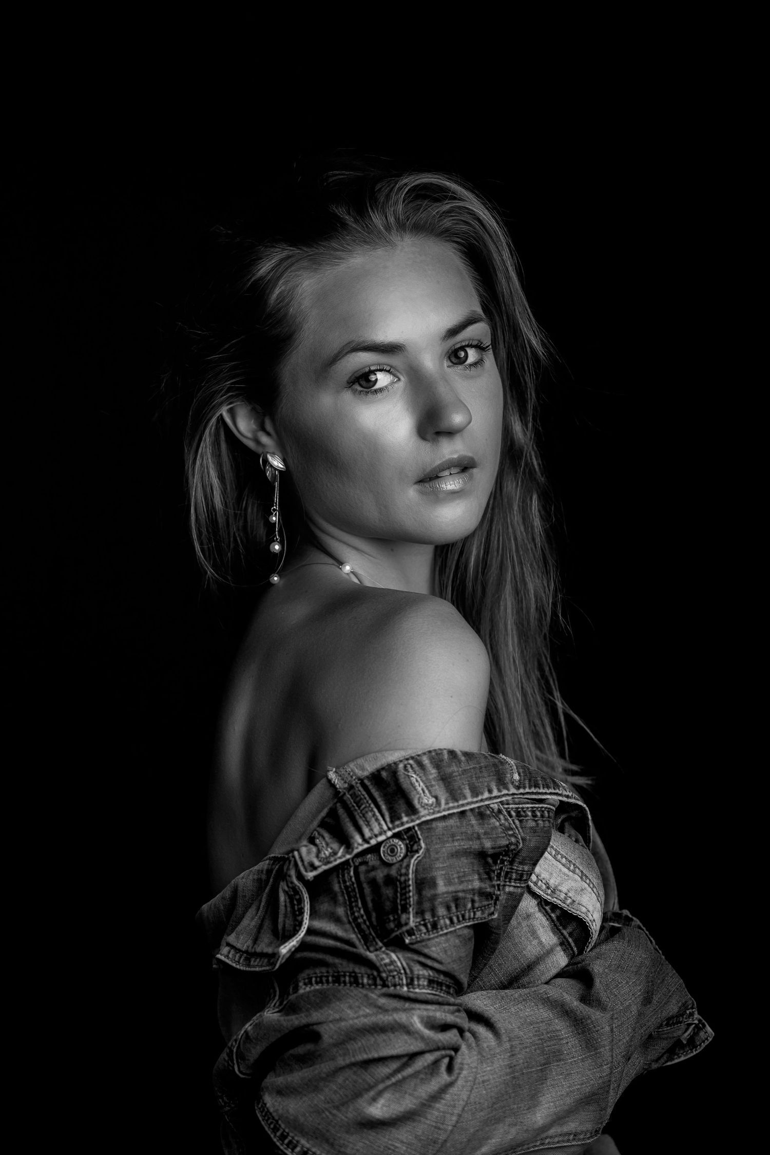 Dramatic black and white portrait series showcasing model in denim jacket with moody lighting and sultry poses.