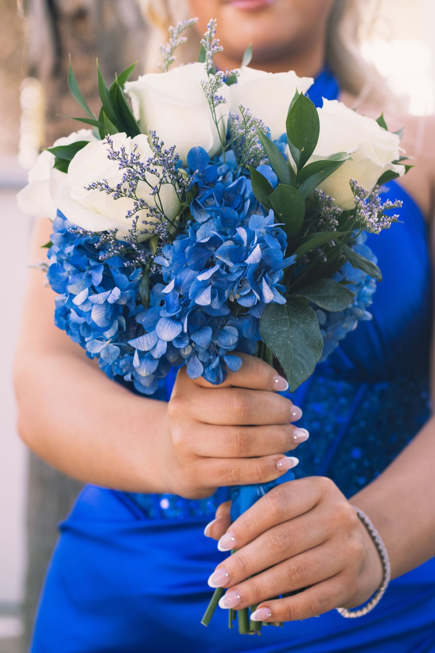 Close-up shots of vibrant blue hydrangea bouquets held against a blue formal dress.