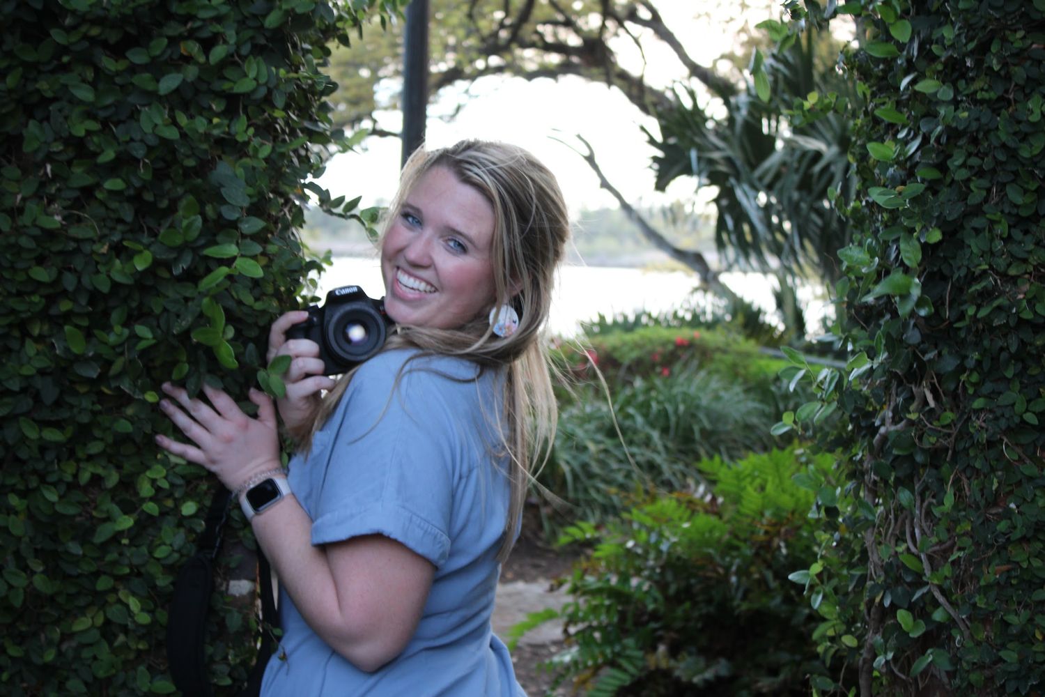 A series of seven similar images showing someone in a gray shirt holding and cuddling with a small black cat outdoors.