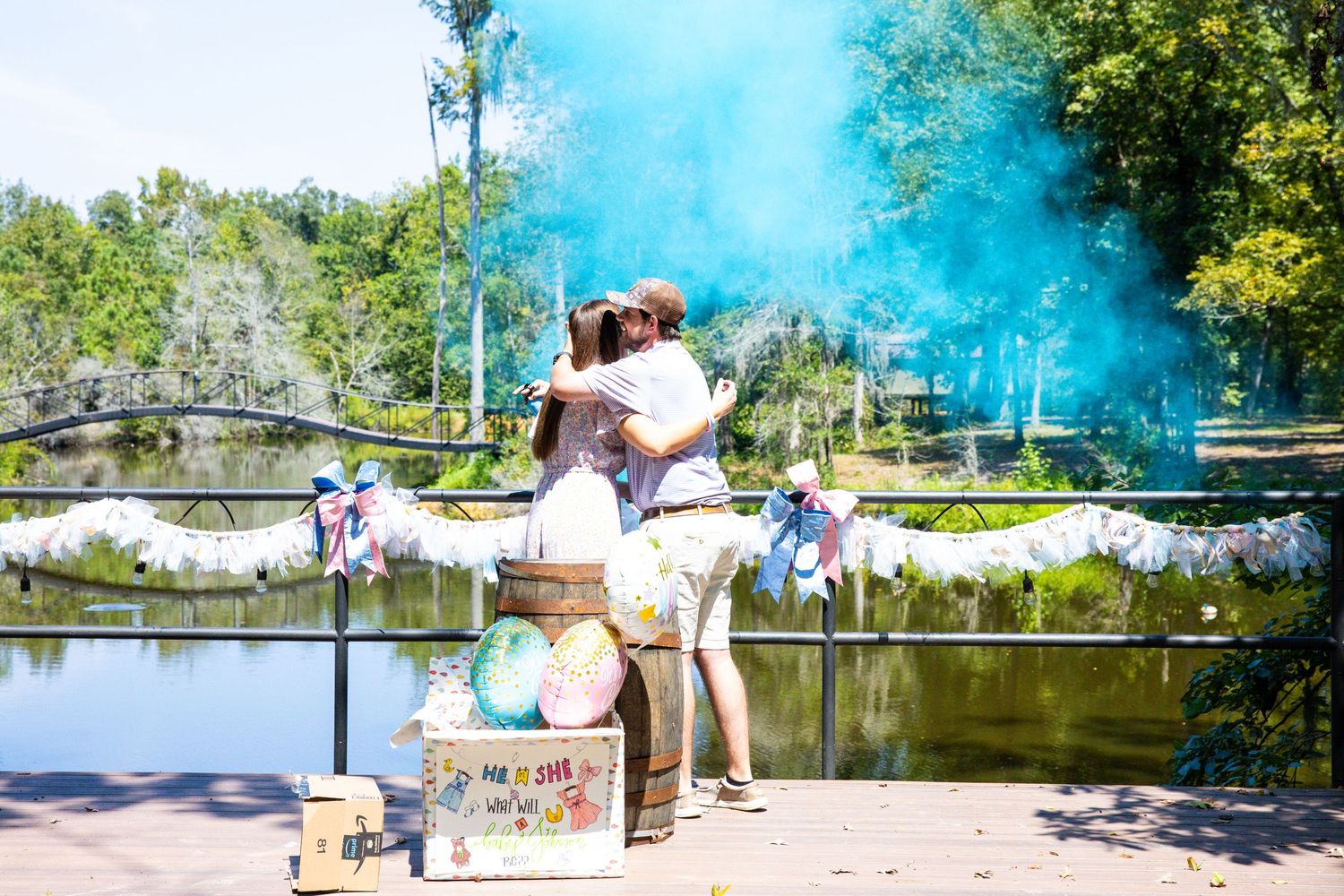 Blue smoke creates a dreamy atmosphere around a stone bridge in a lush garden setting during a summer photoshoot.