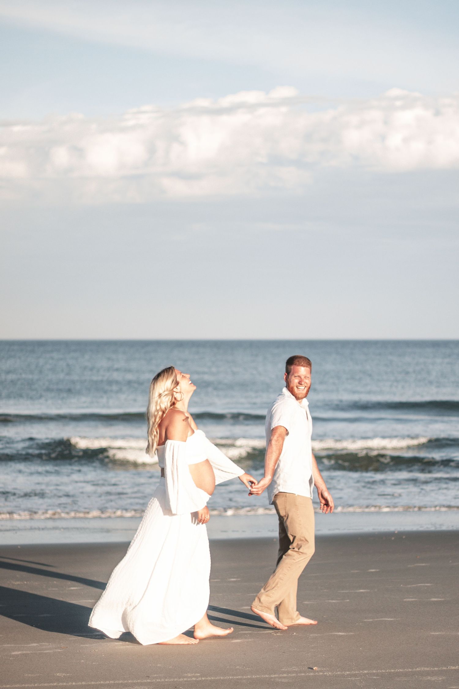 A couple walks hand in hand along a scenic beach during sunset.