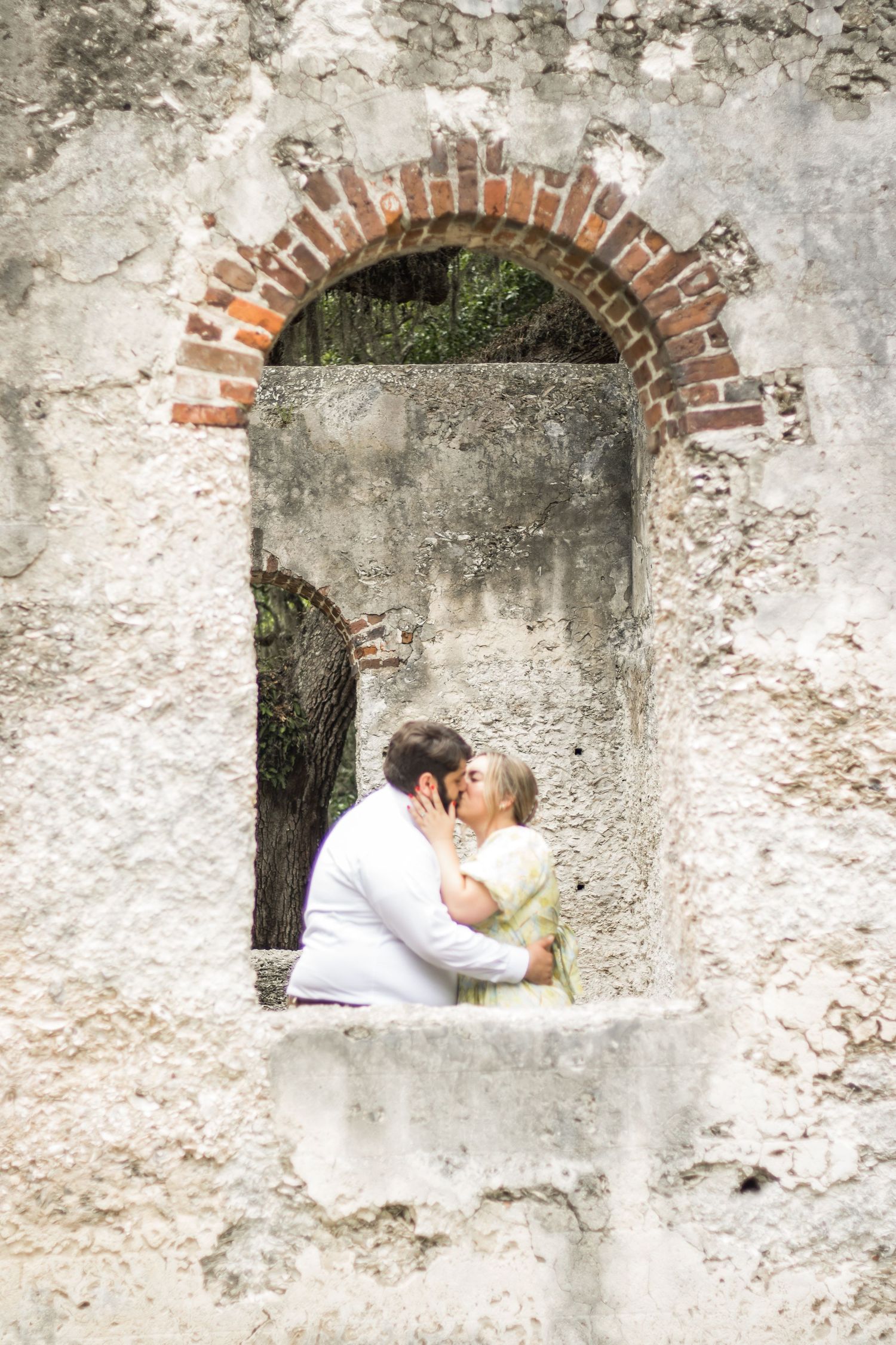 A romantic kiss framed by a rustic stone archway.