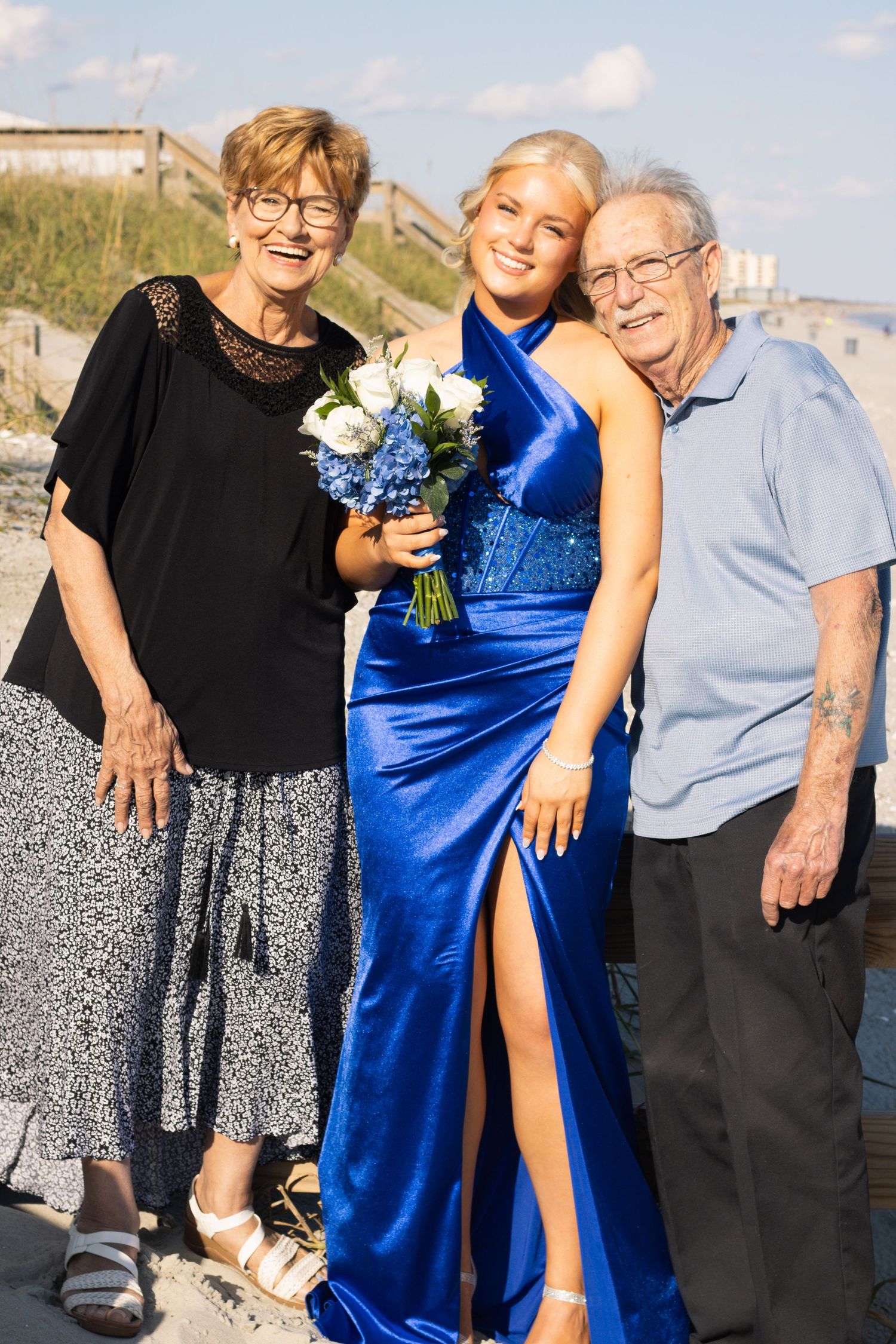 Wedding party members pose together outdoors with one wearing a royal blue formal dress.
