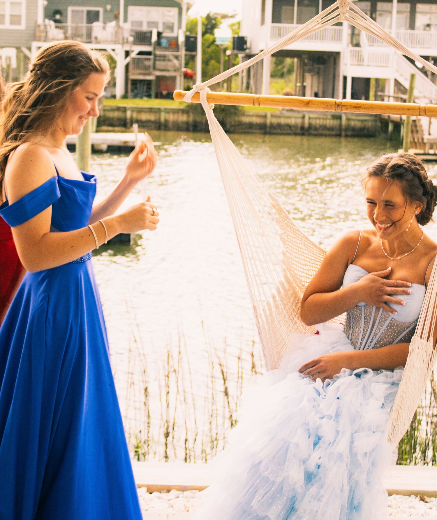 Bridal party celebrating and laughing together on a waterfront dock during sunset.