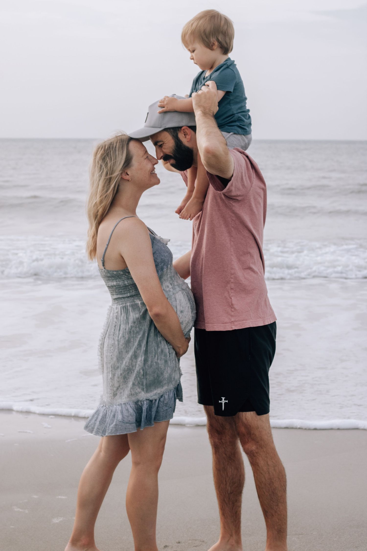 Sweet family moments captured on beach with child and parents playing together.