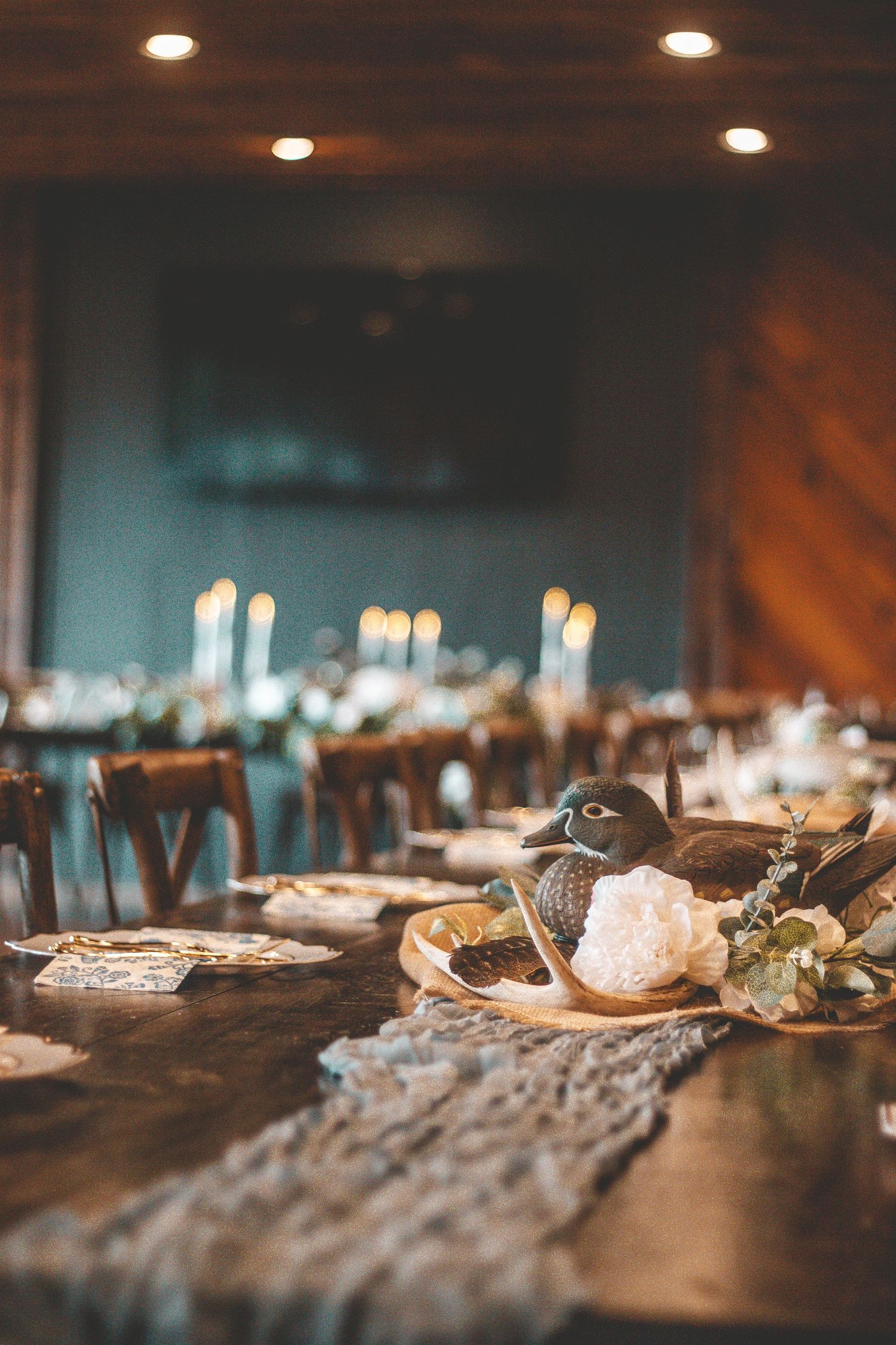 Elegant table setting with candles and rustic decor in a dimly lit reception venue.