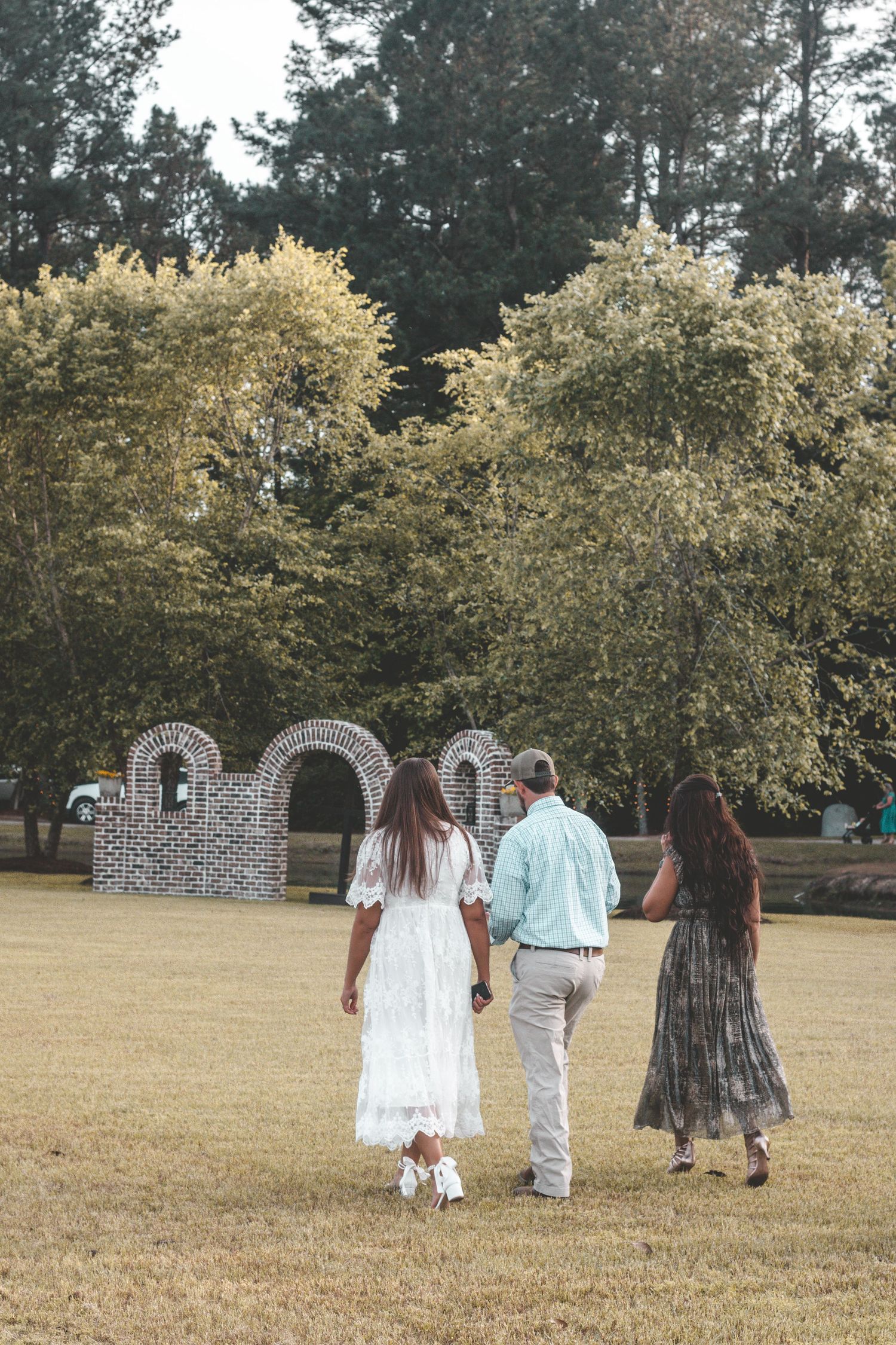 People walking together across a grassy field towards stone architecture in the distance.