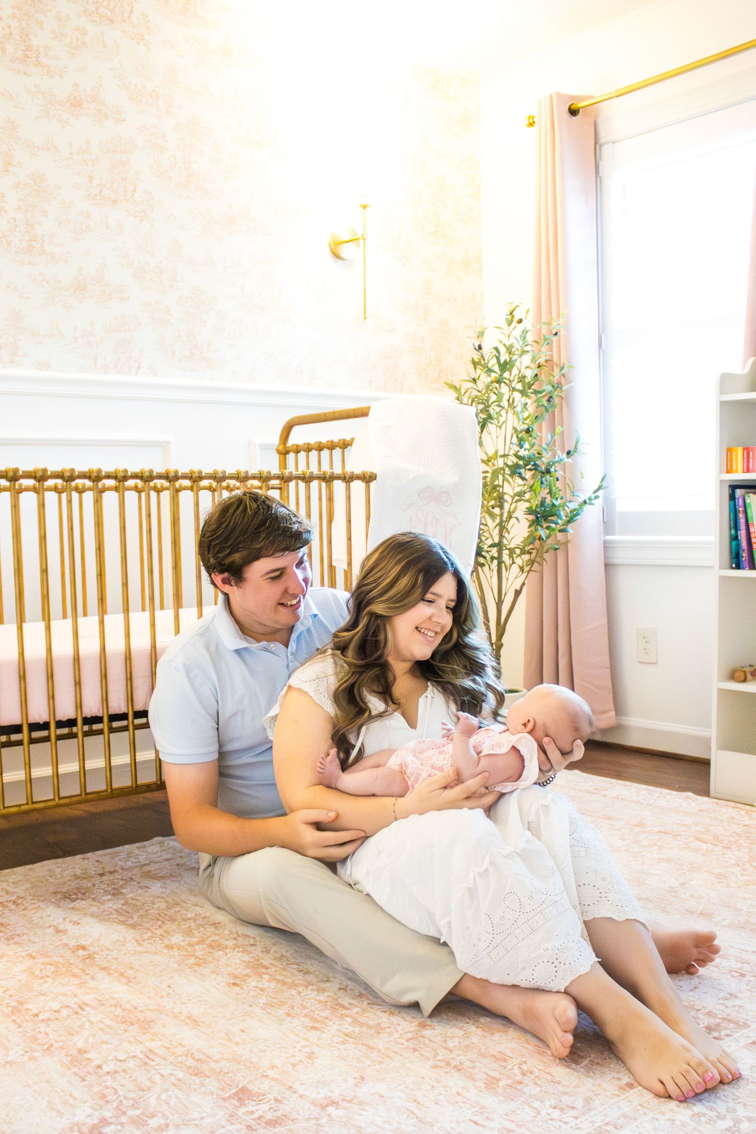 Parents and baby share intimate moments during lifestyle photoshoot in bright nursery setting.