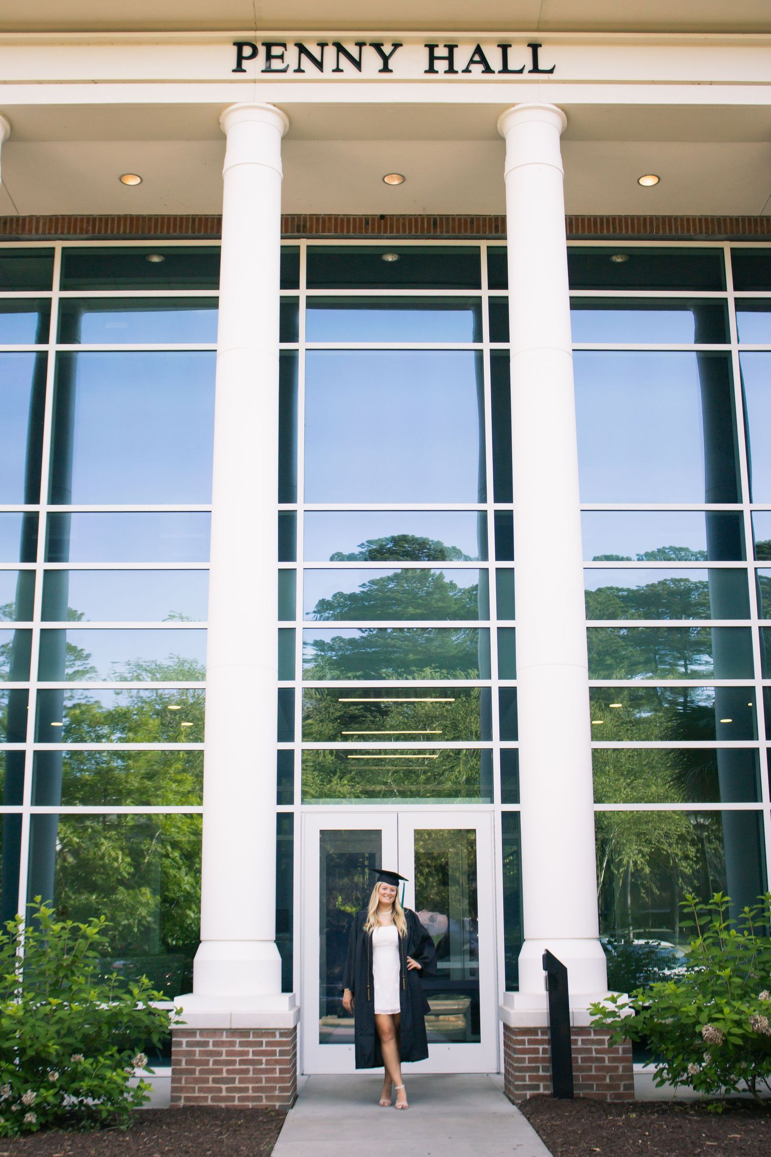 Modern university building exterior of Penny Hall featuring glass windows and white columns.