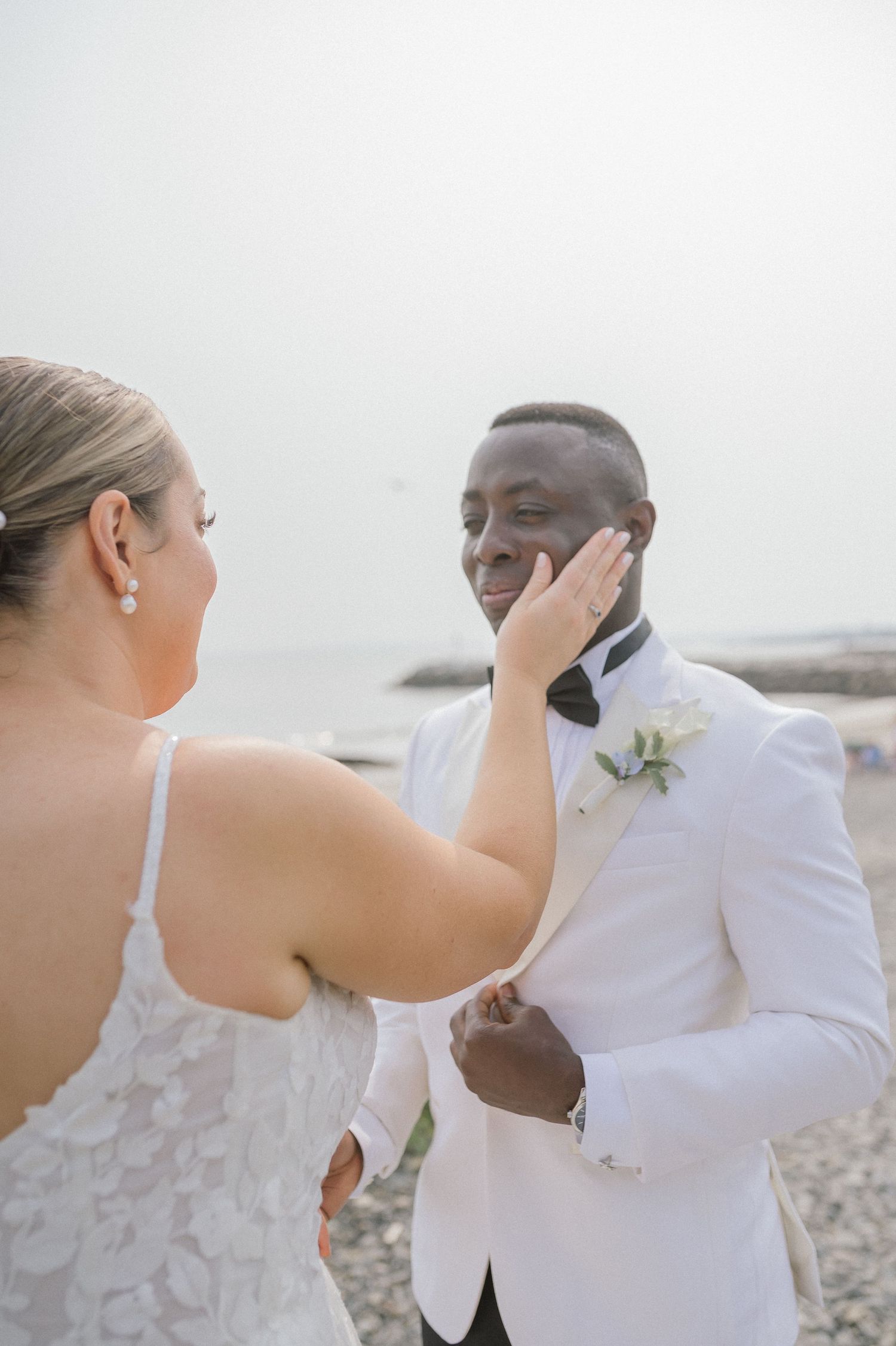 A tender moment between newlyweds on a misty beach shore.