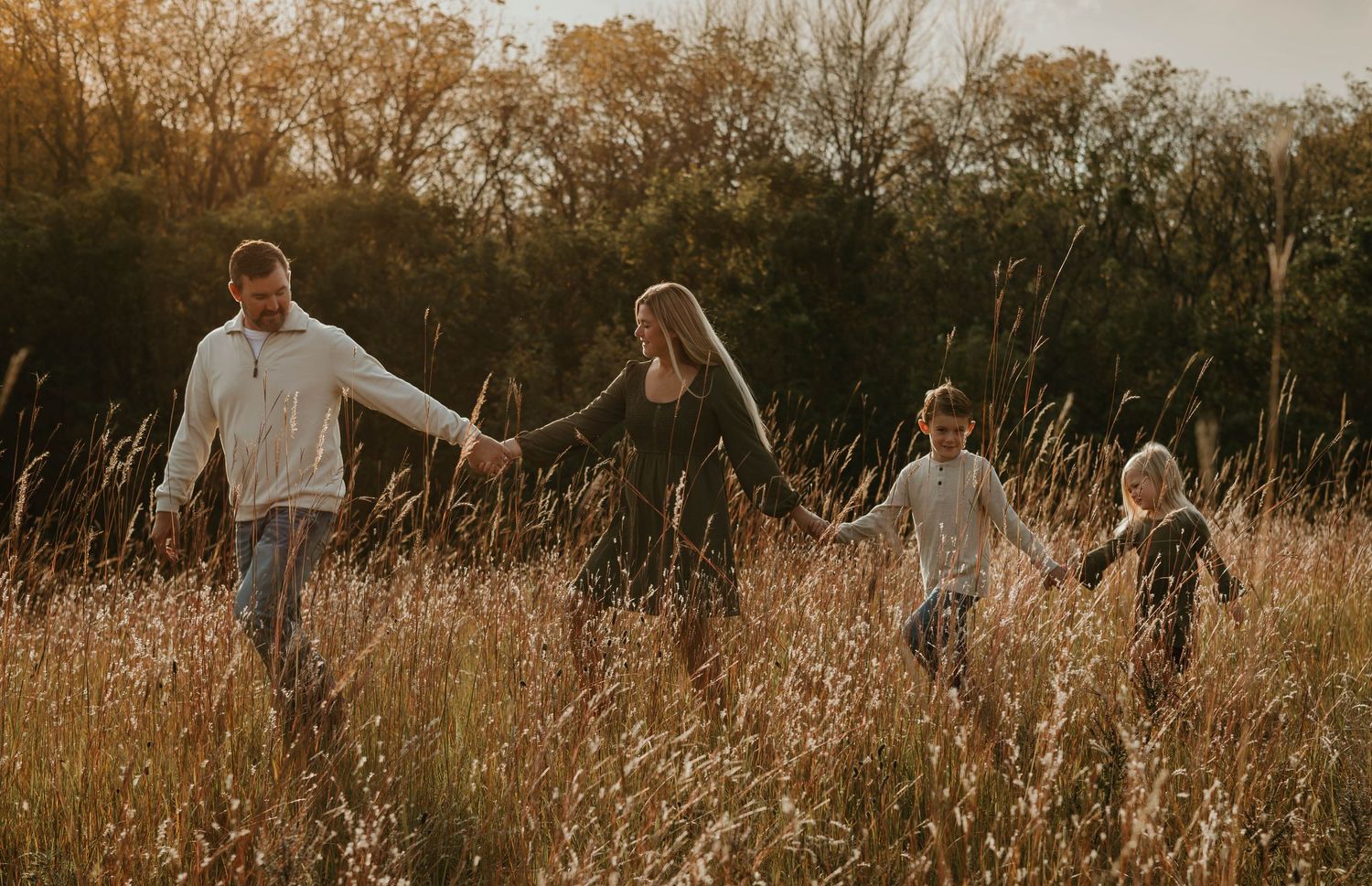 Outdoor family portrait session in tall grass field during sunset.