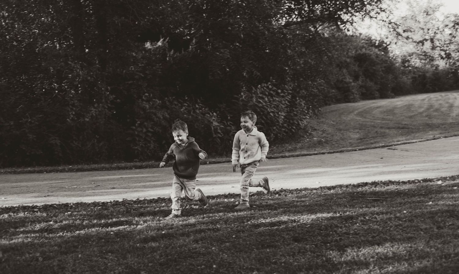 Couple playfully running and dancing together in a grassy field at sunset.