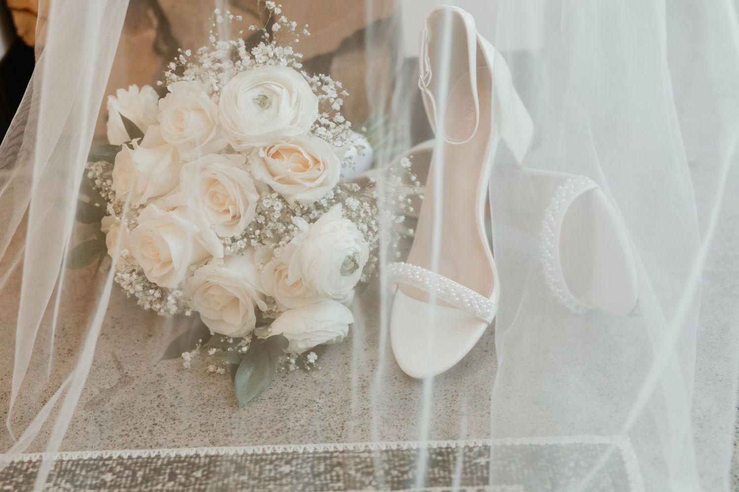 White roses and baby's breath flowers arranged with delicate tulle fabric create an elegant wedding setting.