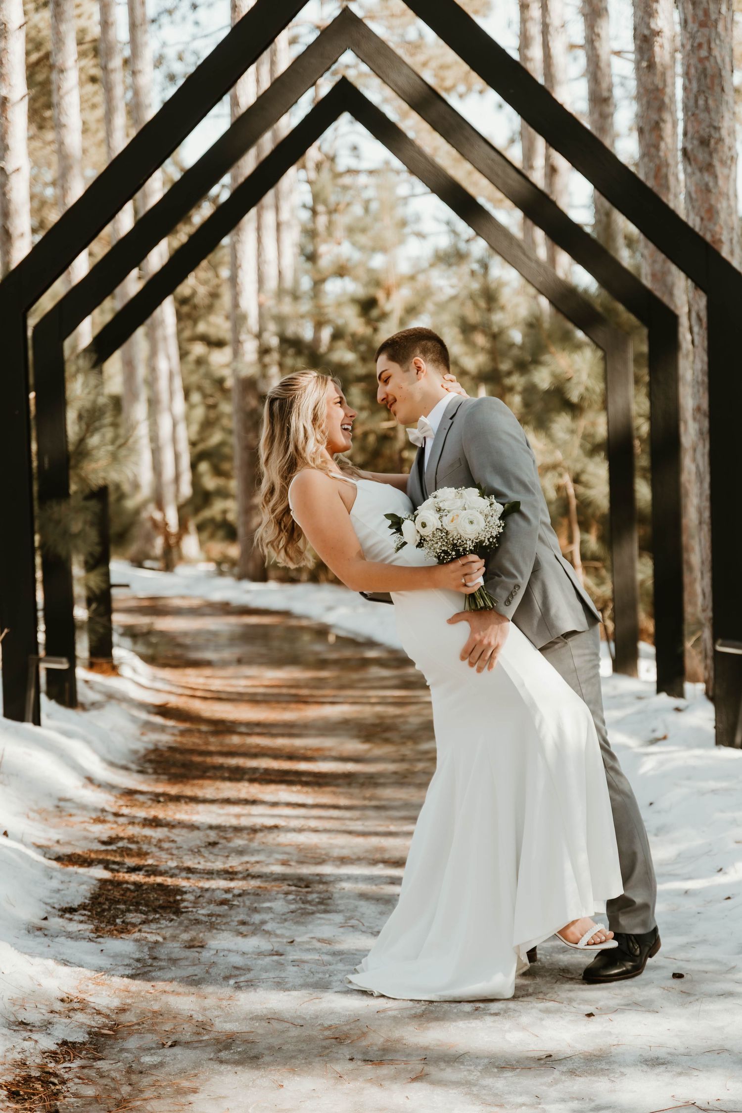 A romantic winter wedding photo sequence showing a couple dancing and dipping in a snowy forest path.