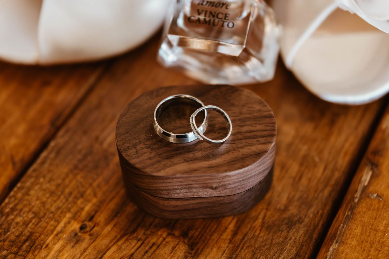 Two silver wedding rings rest on a rustic wooden surface in natural lighting.