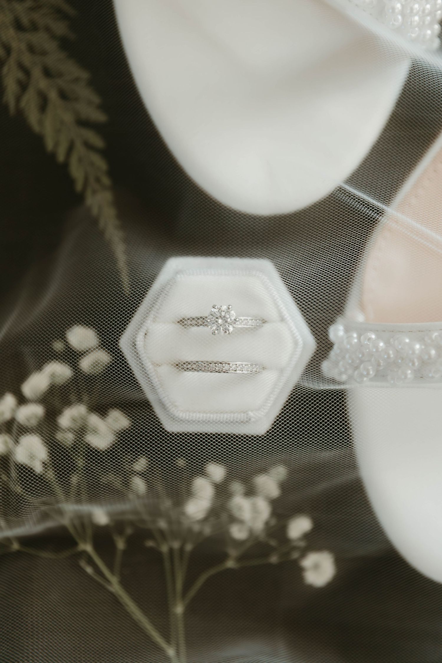 Close-up view of an elegant diamond engagement ring in a white box with delicate baby's breath flowers.