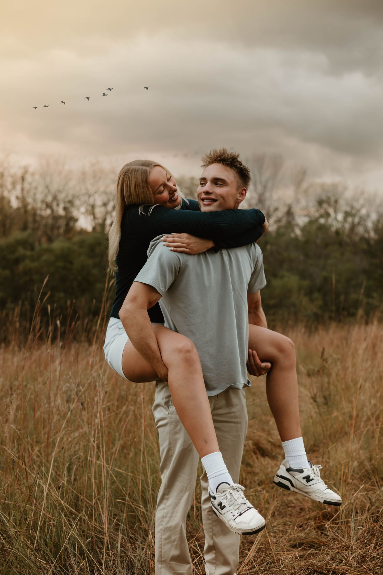 A playful piggyback ride in a golden field at sunset with birds flying overhead.