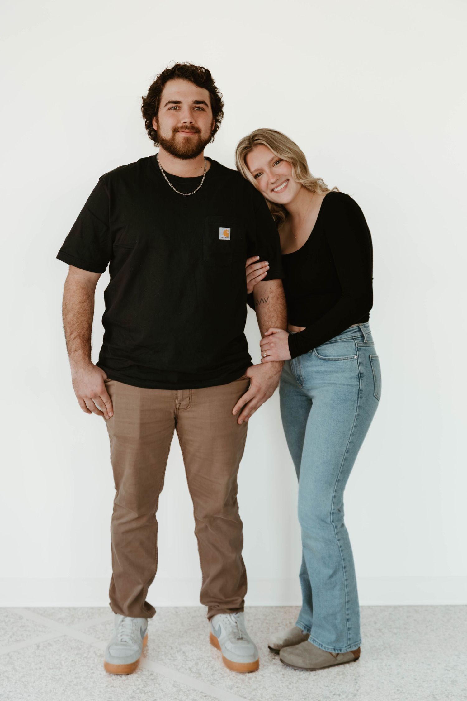 A couple poses together against a white background in a series of casual lifestyle photos.