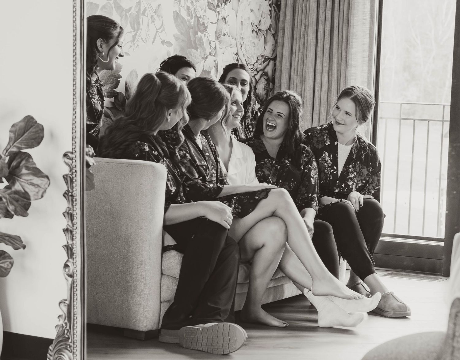 A group of women sit together in a casual setting, looking at papers and sharing conversation in a vintage black and white photo.