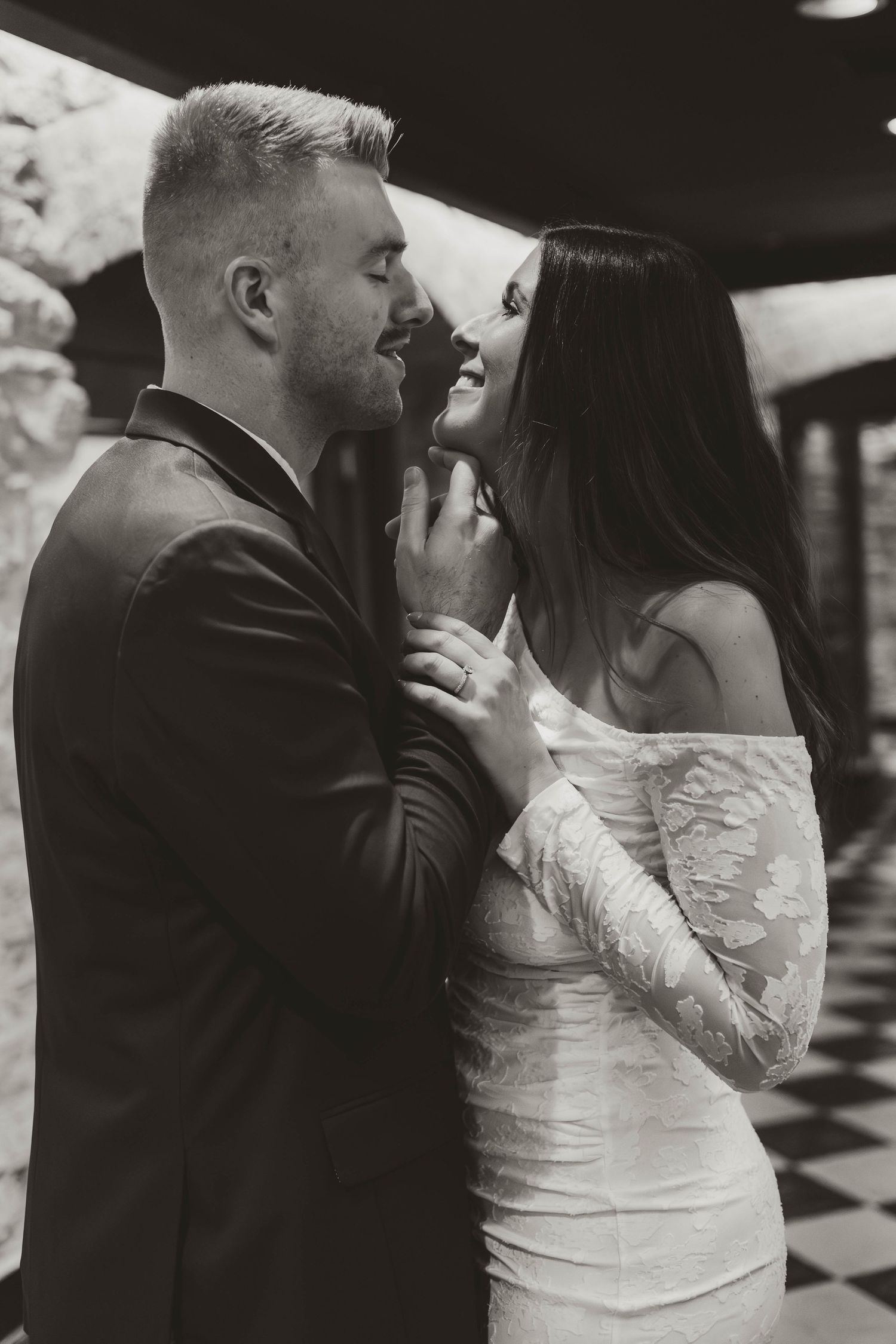 Romantic couple dancing together on a black and white checkered floor during their wedding celebration.