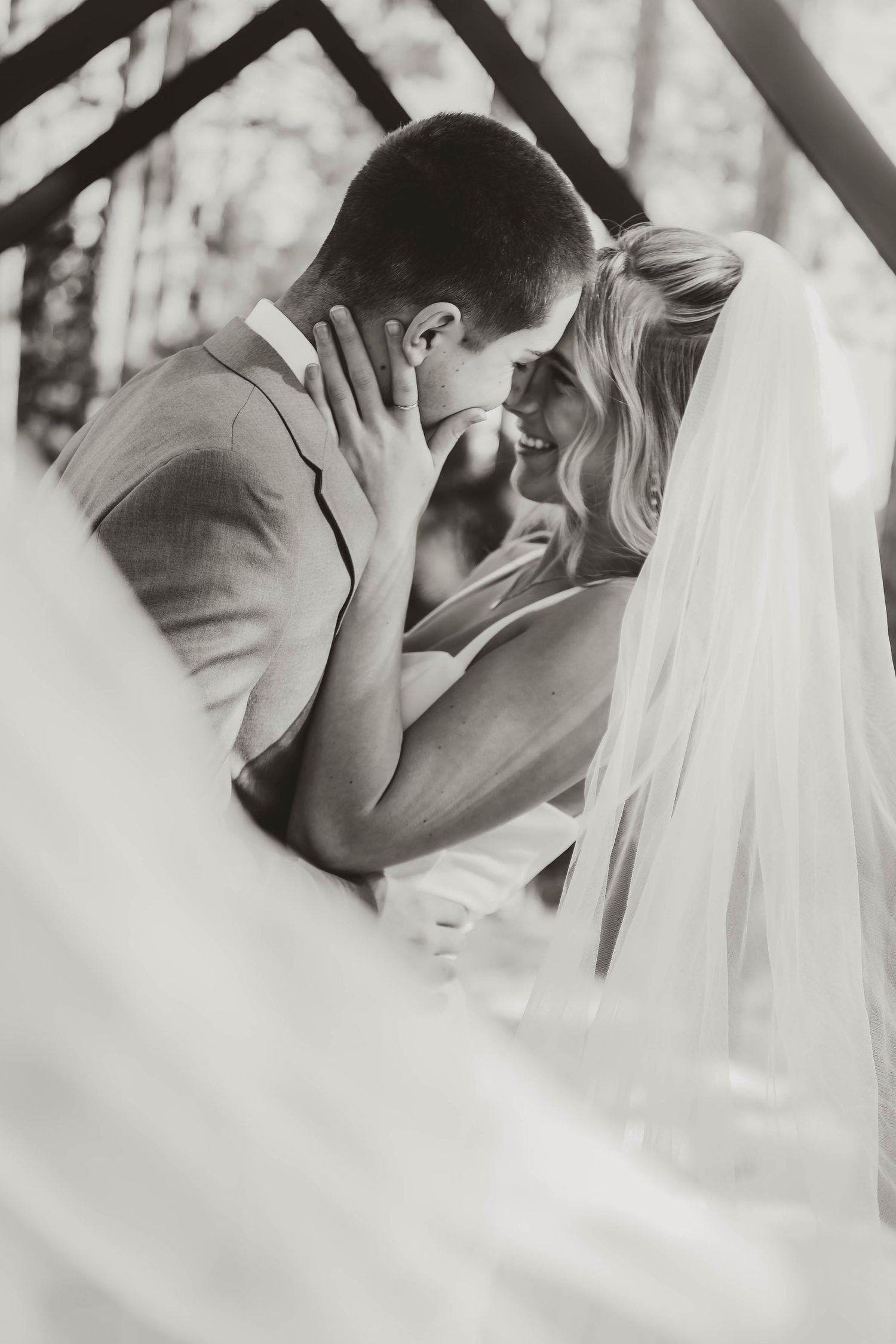 Black and white intimate wedding moment captured through flowing veil.