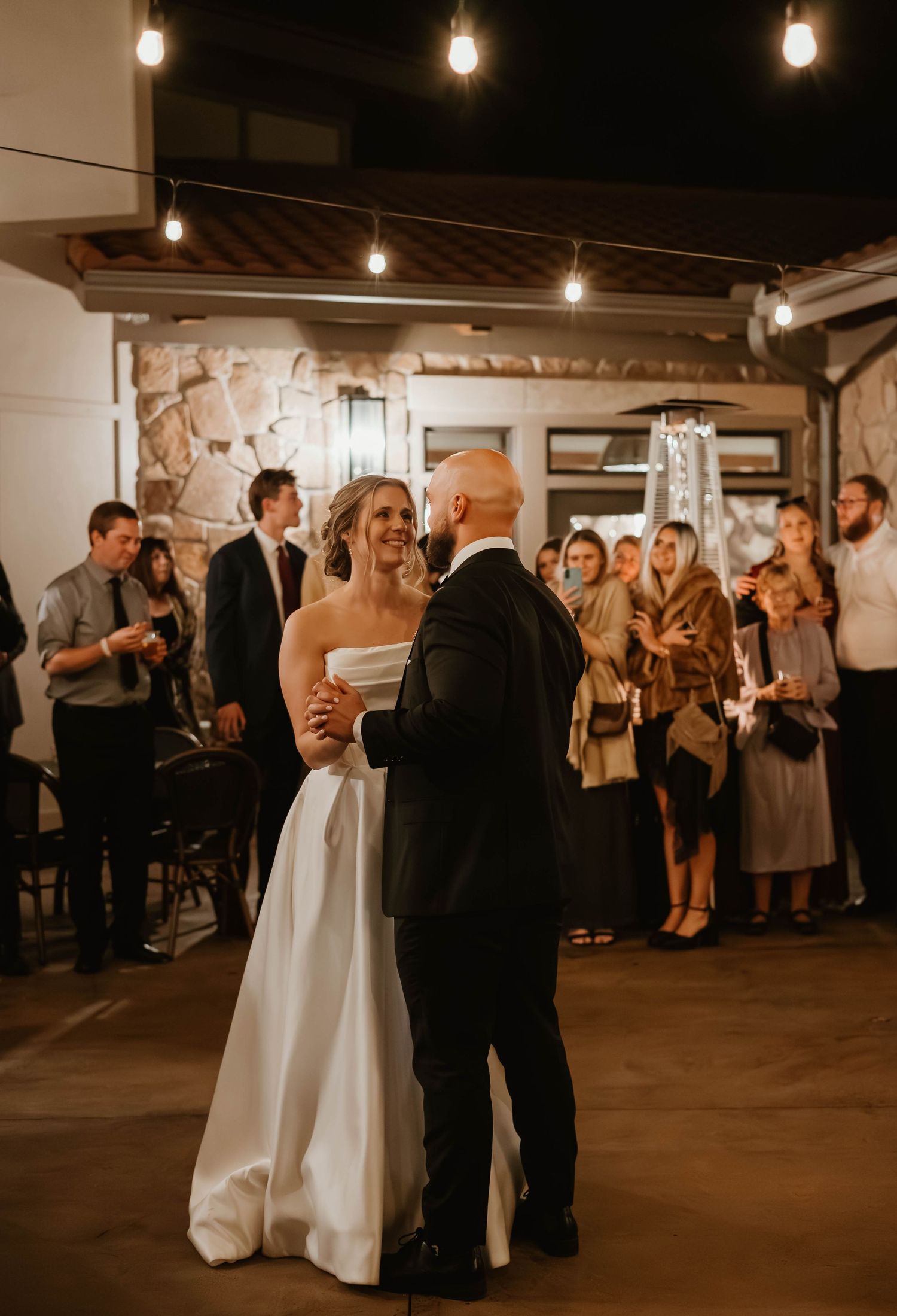 Wedding reception in a rustic venue with exposed brick walls and hanging Edison bulbs.