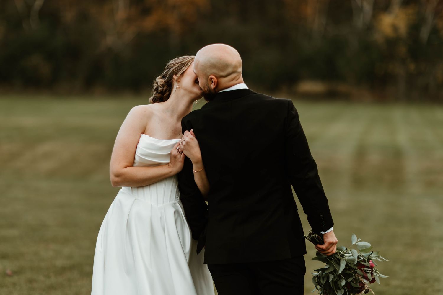 Romantic wedding couple embracing in golden autumn field.